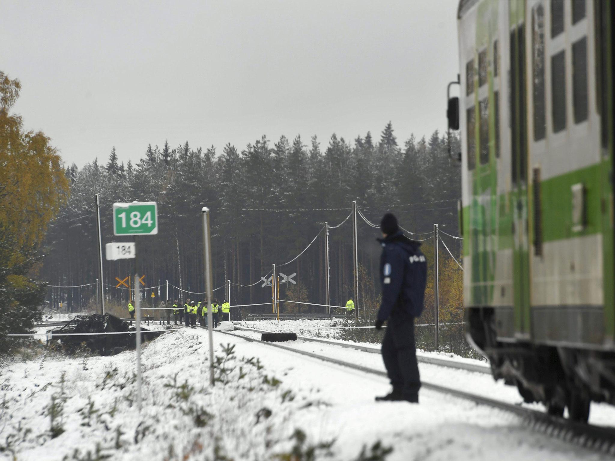 Rescue personnel and the damaged wreckage of a military truck are seen at a rail crossing near Raseborg in Finland