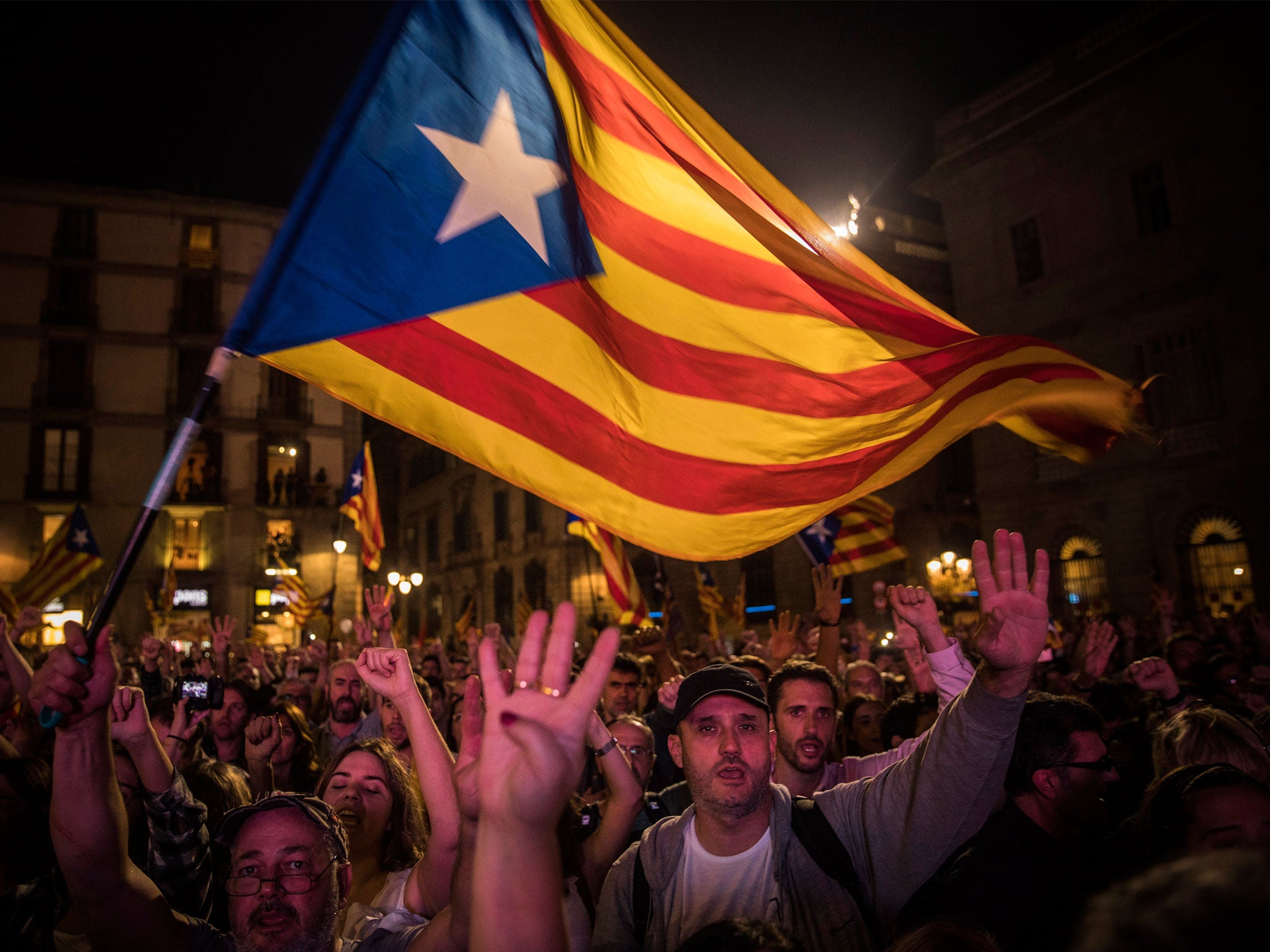 Pro-independence supporters cheer and wave "estelada" or pro independence flags in the square outside the Palau Generalitat in Barcelona