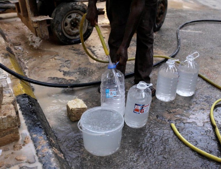 A man fills bottles and a bucket with water in Tripoli, Libya