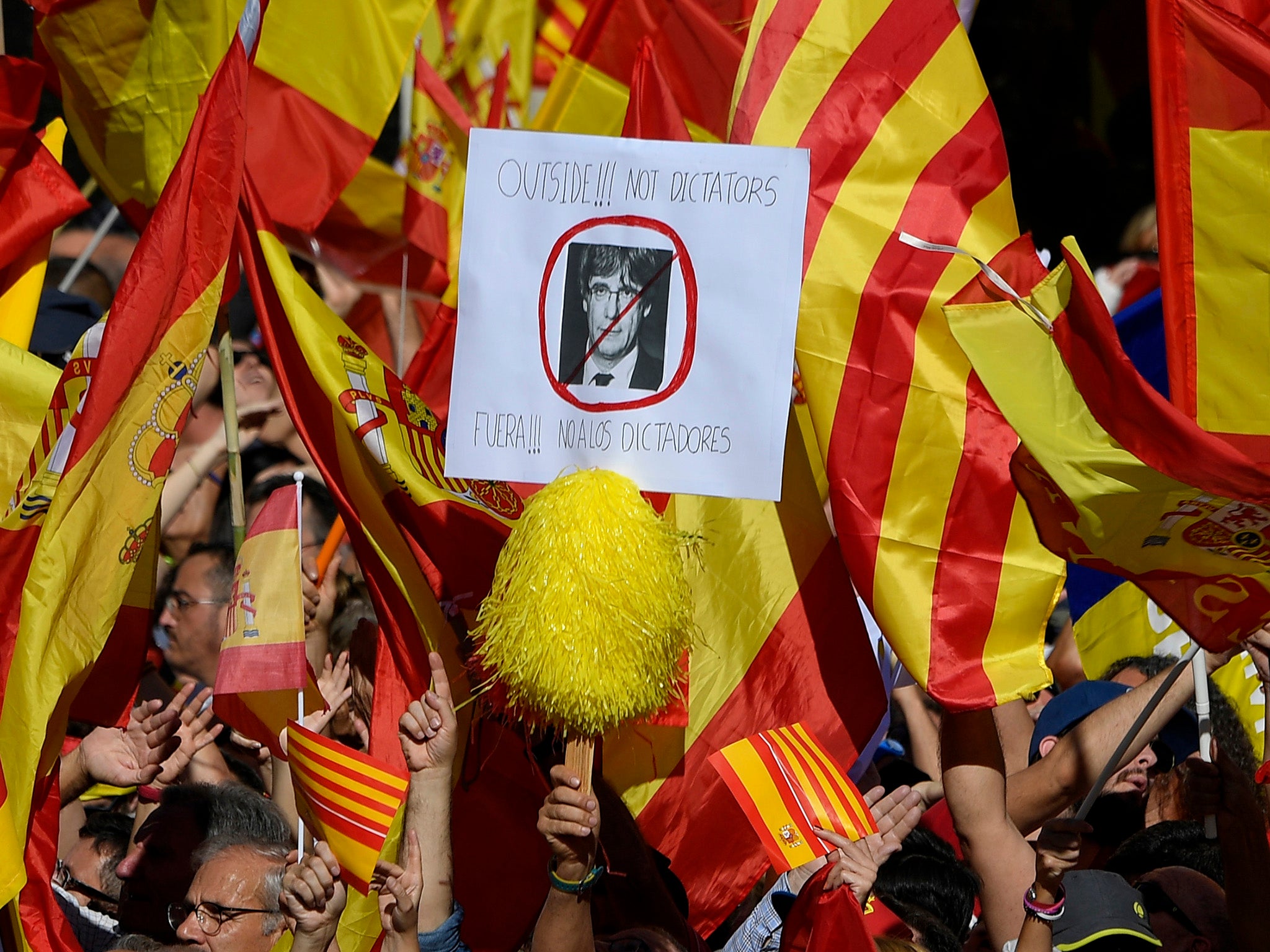 An anti-independence protester holding a portrait of Carles Puigdemont reading 'Dictators Out'. Thousands of protesters were out on the street to demand Catalonia remains part of Spain