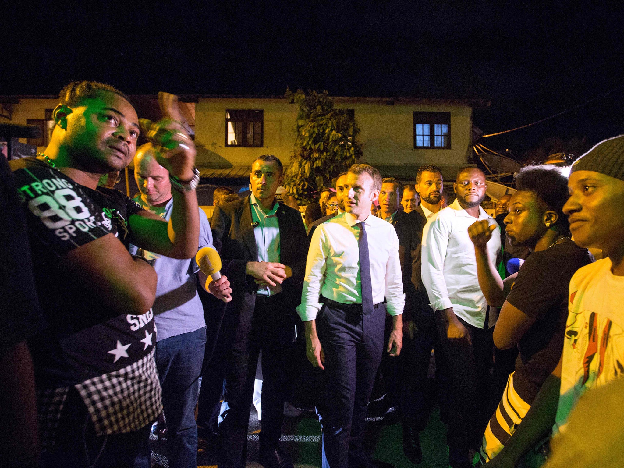 French President Emmanuel Macron speaks with residents during a visit to the Crique neighborhood in Cayenne as part of a three-day visit to French Guiana