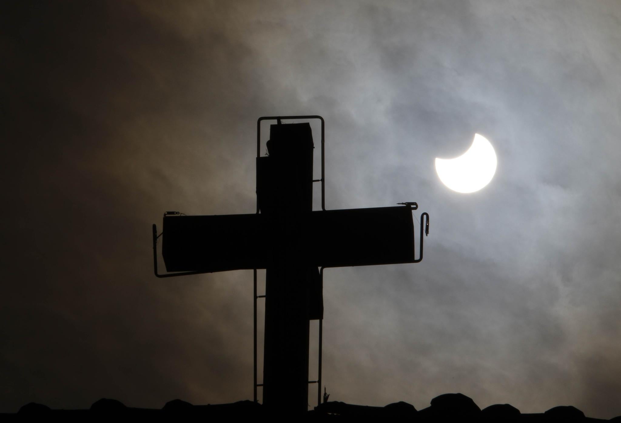 A picture taken on January 4, 2011 in Old Damascus shows the world's first partial solar eclipse of 2011 behind the cross of a church in a Christian neighbourhood of the Syrian capital