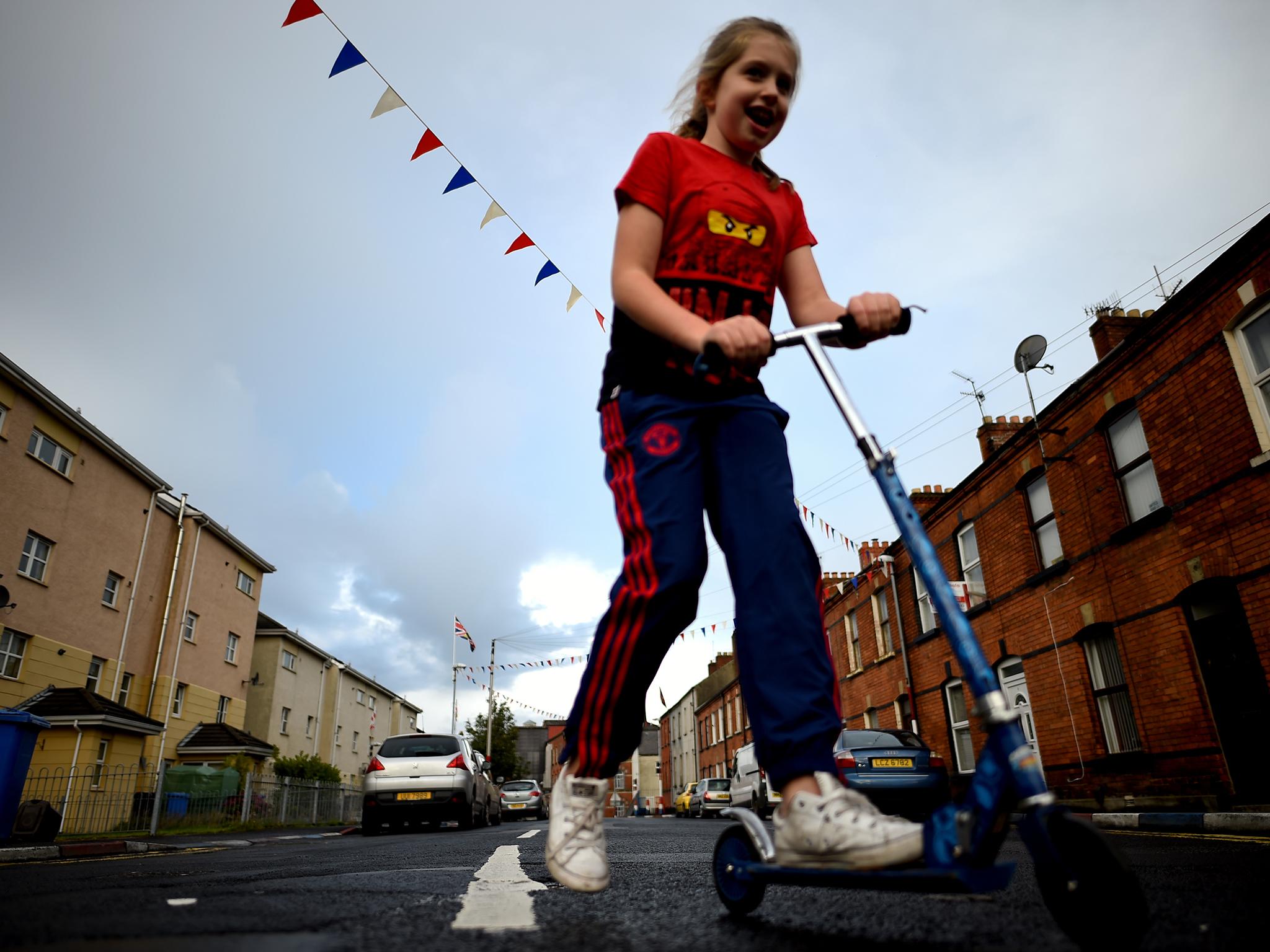 A girl rides her scooter in the walled-off loyalist Protestant enclave called The Fountain, situated within the city of Derry