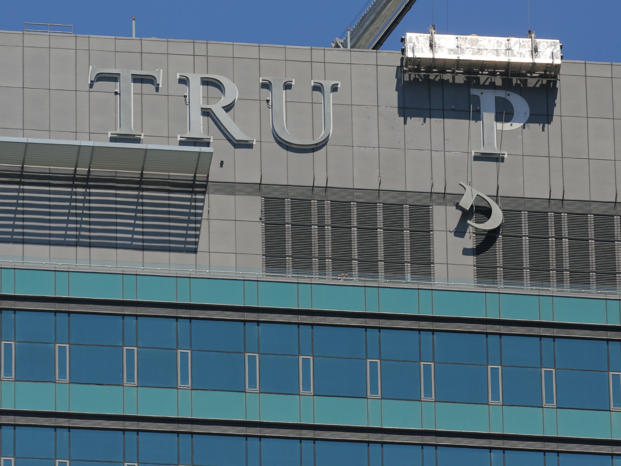 Workers remove letters from the "TRUMP" sign on top of the Trump International Hotel and Tower, after the project's new owner reached a deal with Trump Hotels to buy out its management contracts, in downtown Toronto, Canada on July 18, 2017