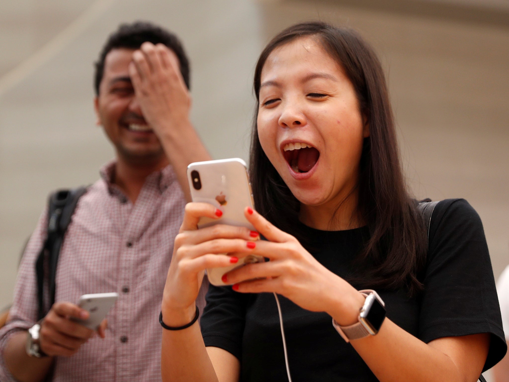 People try the Animoji feature on iPhone X during its launch at an Apple store in Singapore