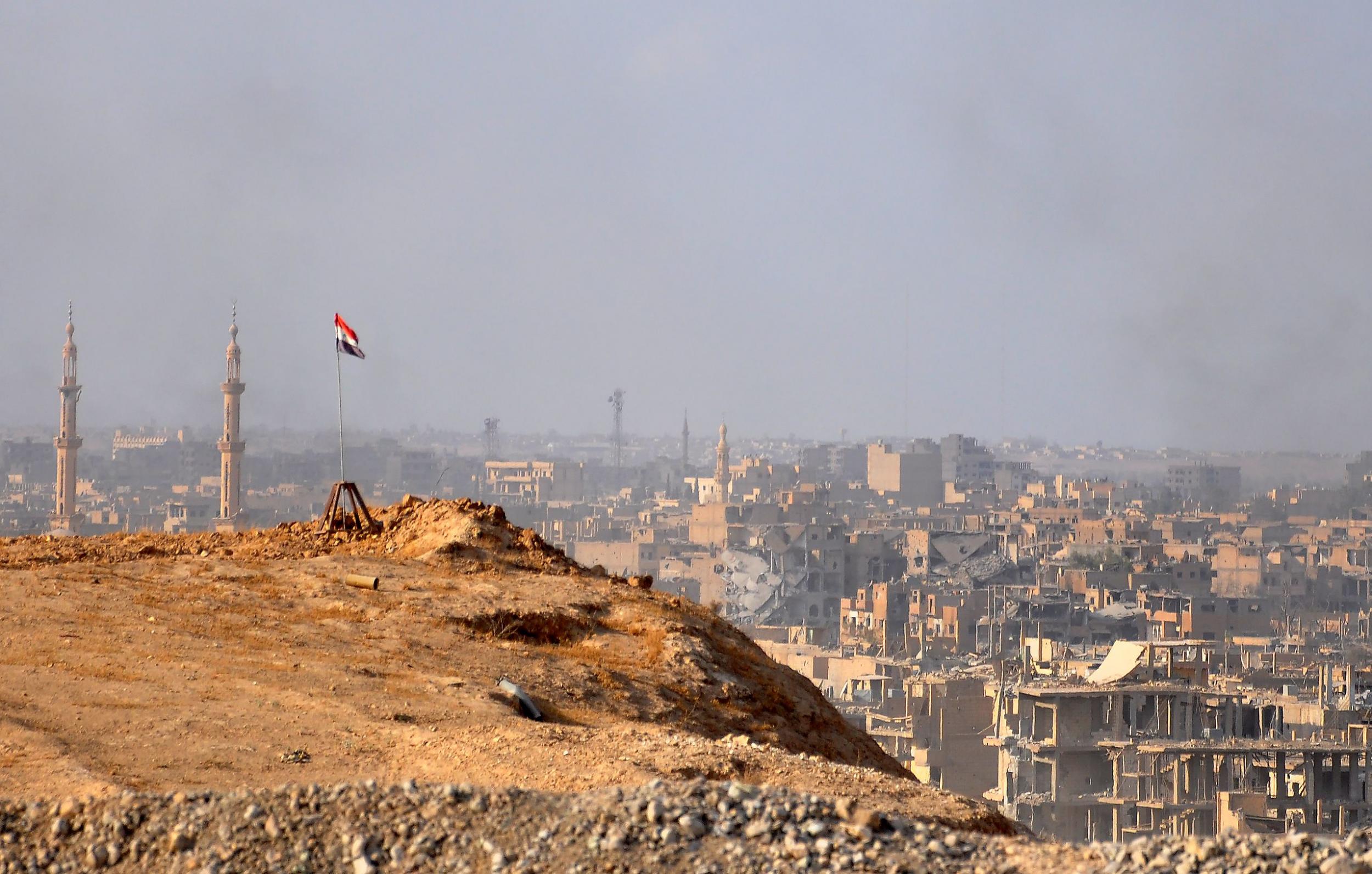 A Syrian flag flies over Deir Ezzor as government forces fight Isis militants on 2 November