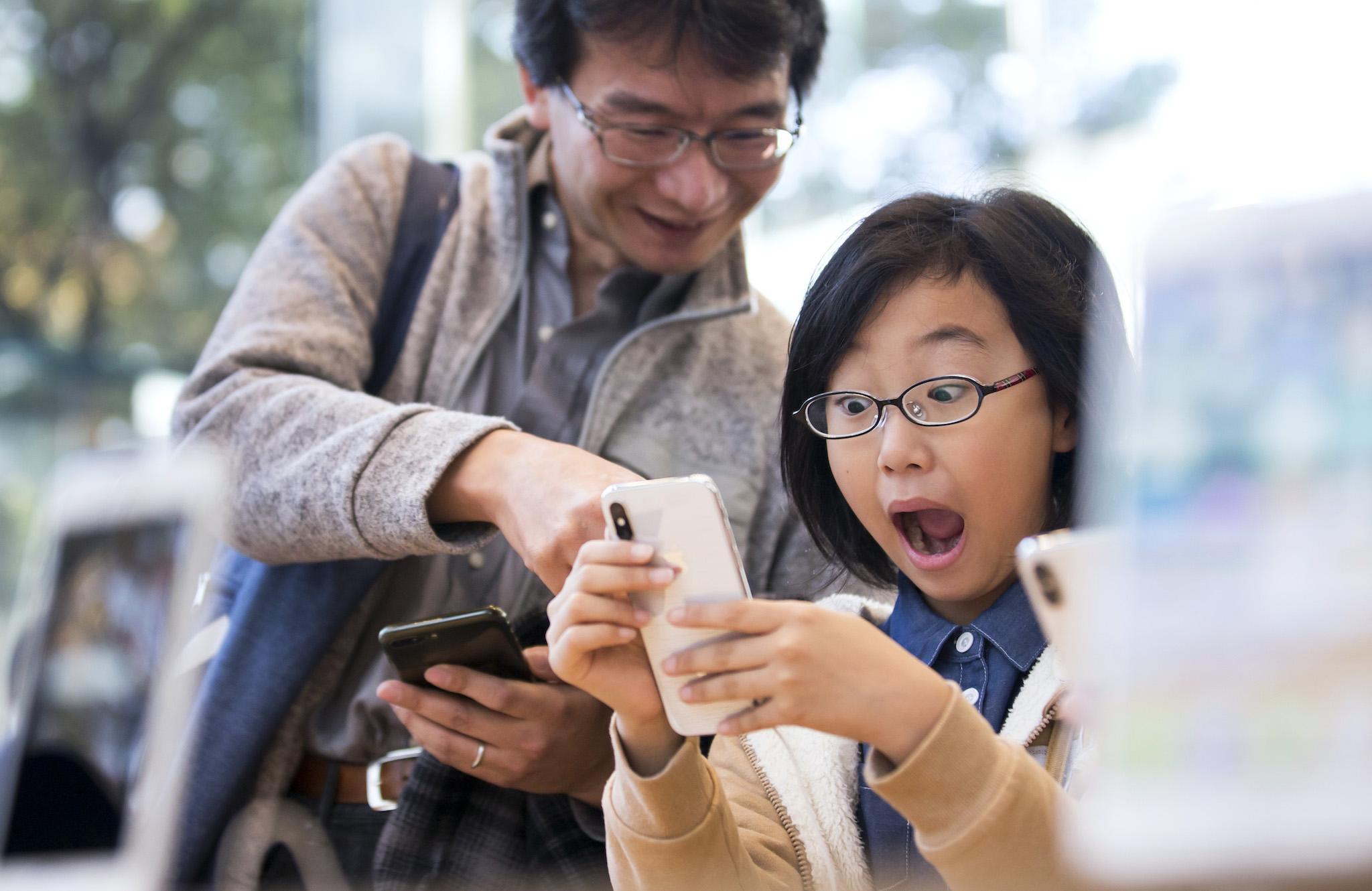 A girl reacts as she tries an iPhone X at the Apple Omotesando store on November 3, 2017 in Tokyo, Japan