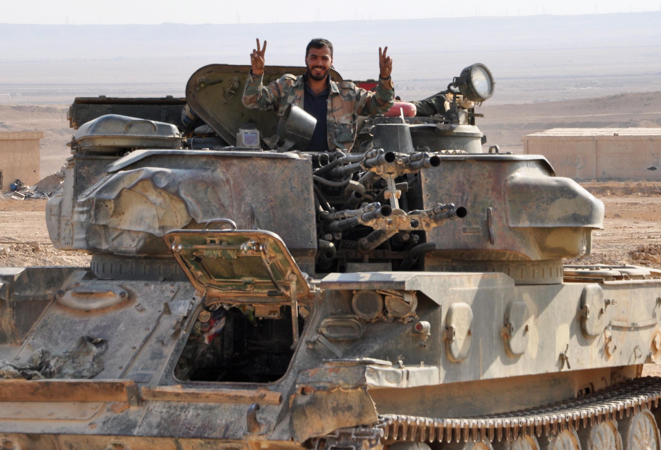 A Syrian soldier flashes a ‘V for Victory’ sign from his tank