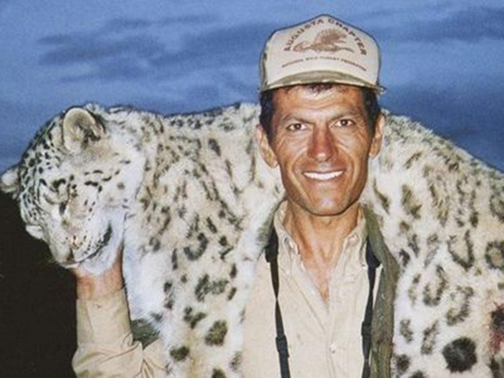 Hossein Golabchi smiles with the big cat draped over his shoulders, which appears to have been shot twice in its hind leg