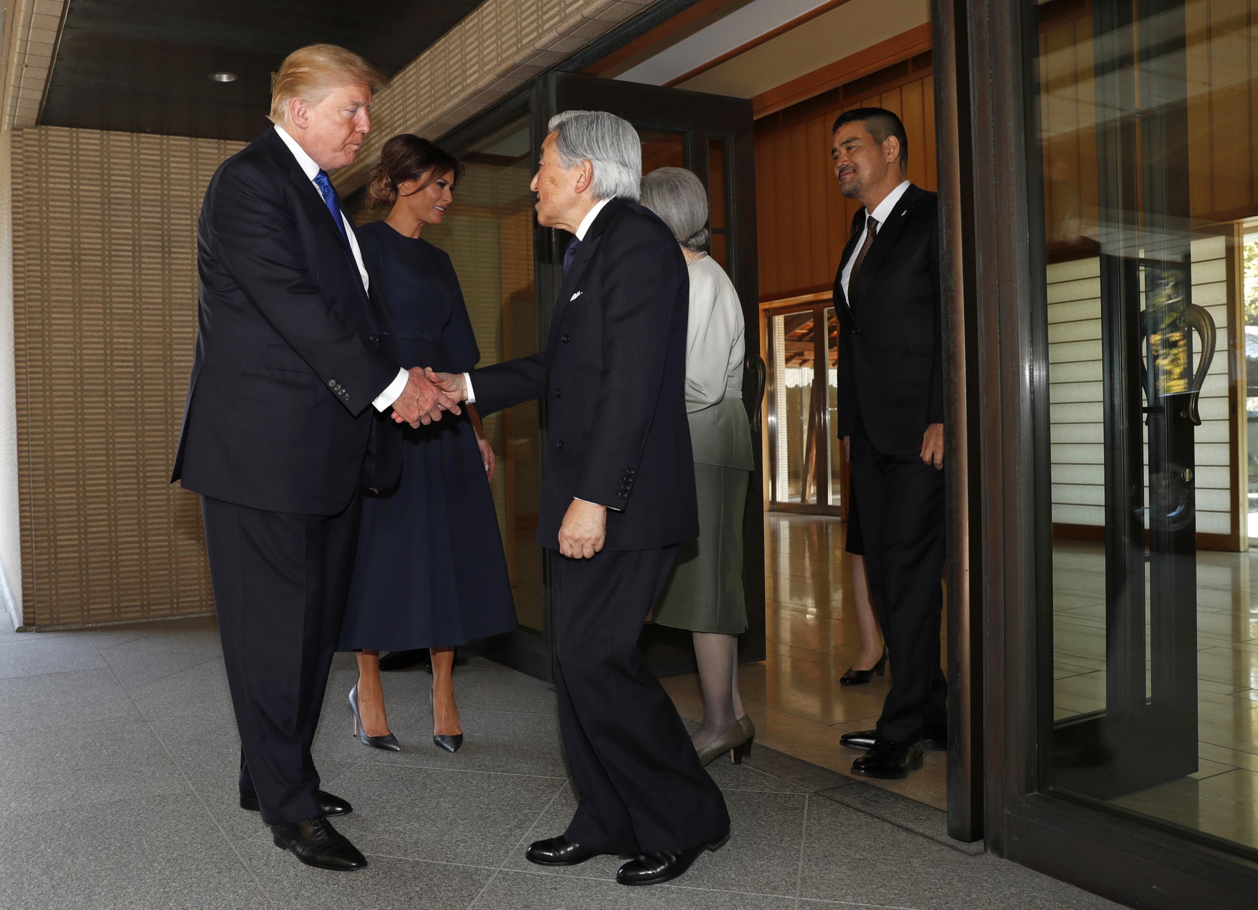 Donald Trump shakes hands with Japan's Emperor Akhito as first lady Melania Trump speaks to Empress Michiko