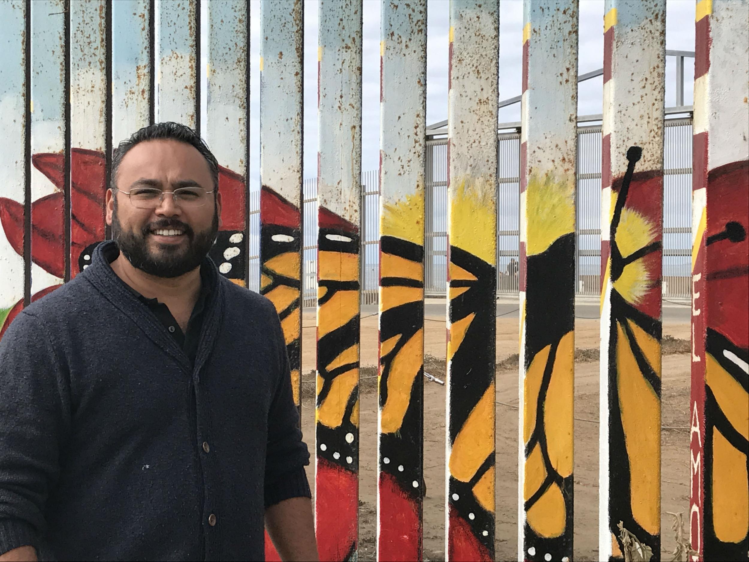 Enrique Chiu shows off work he and his friends have done on the wall in Tijuana