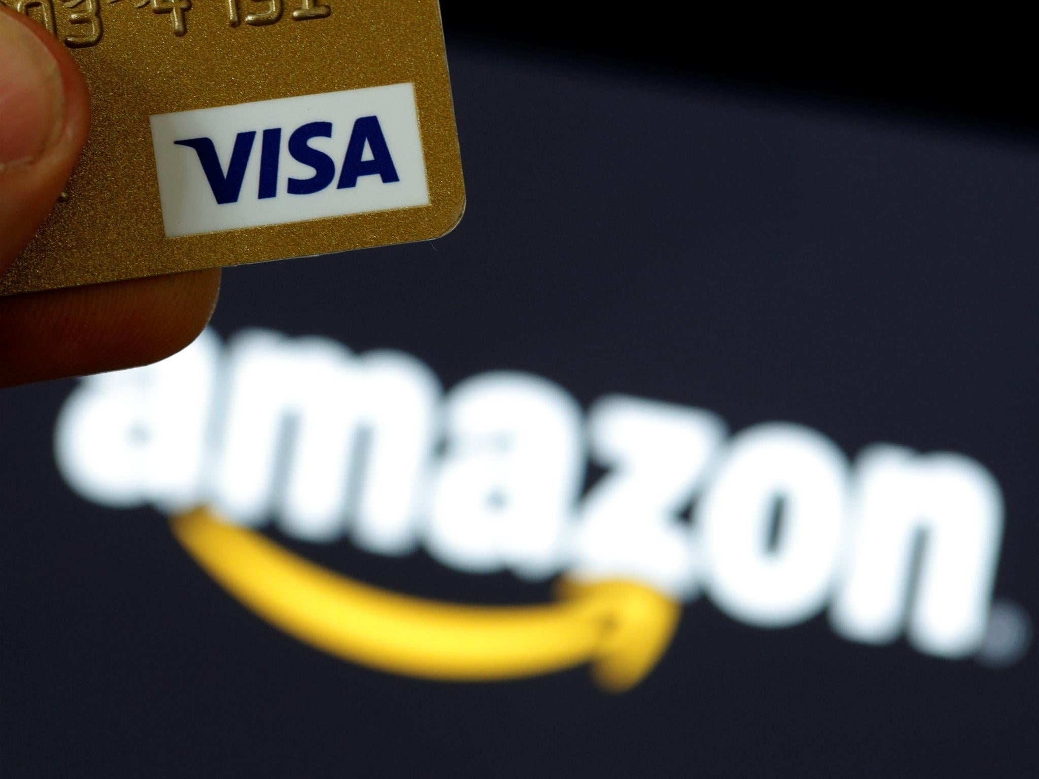 A visa credit card is held in front of an Amazon logo in this picture illustration taken September 6, 2017