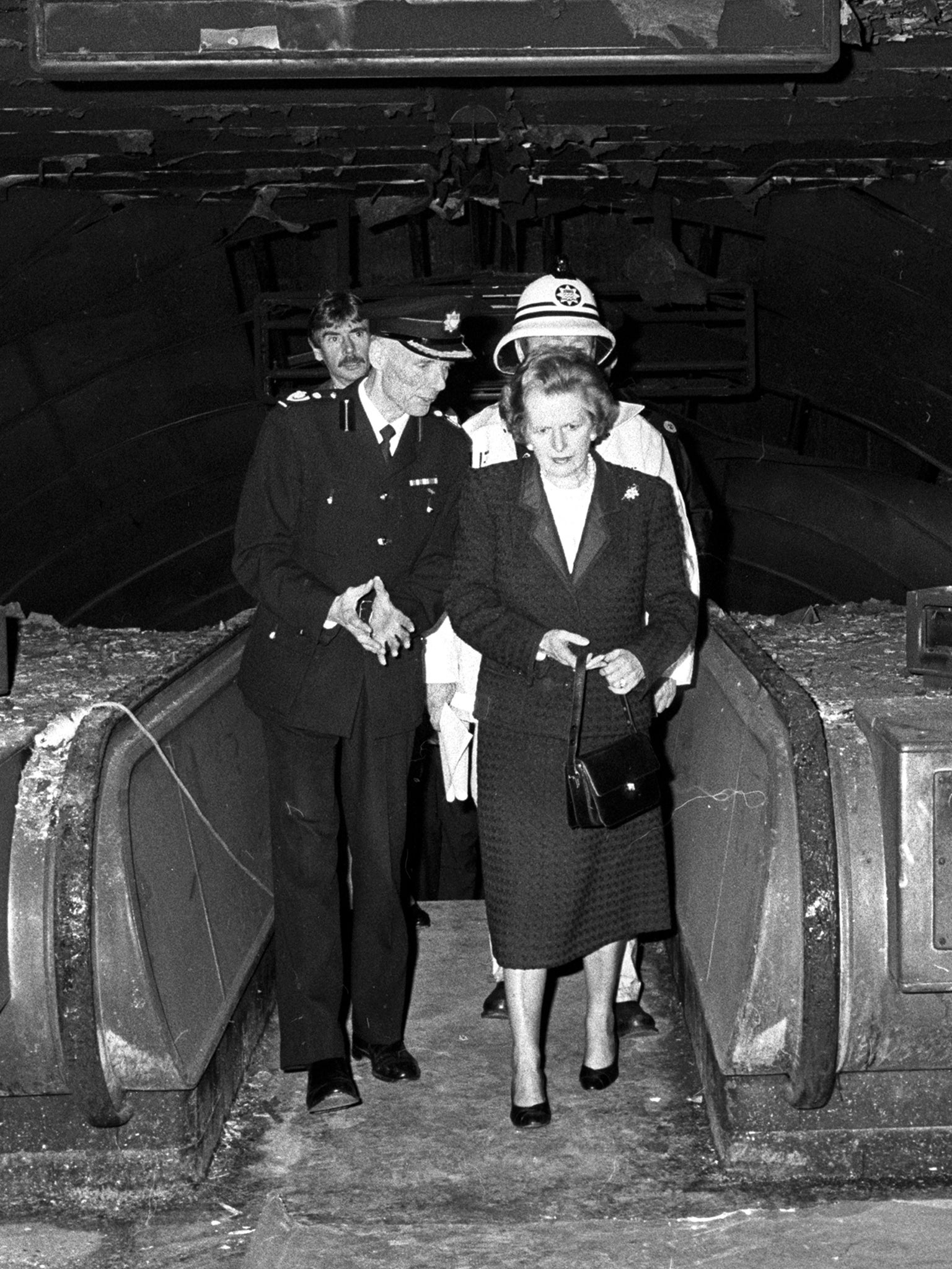 Margaret Thatcher, escorted by deputy chief fire officer Mike Doherty, tours the fire-damaged ticket hall (PA)