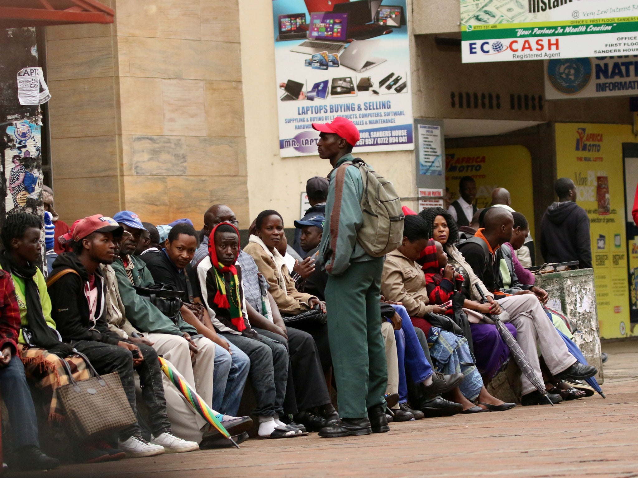 People queue to draw money outside a bank in Harare, Zimbabwe