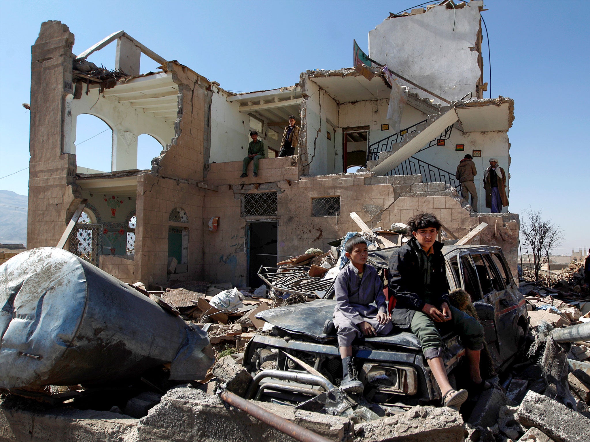 Children sit amidst the rubble of a house hit by Saudi-led coalition planes