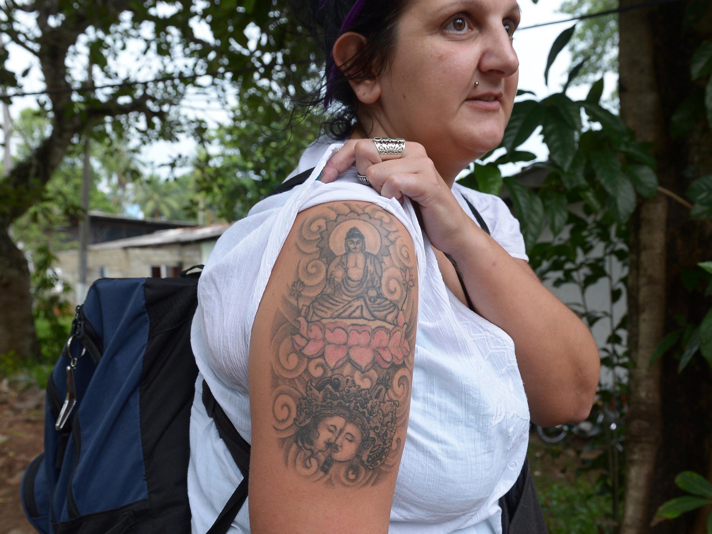 British tourist Naomi Coleman poses for a photograph to display a tattoo of the Buddha on her upper arm, after she was arrested at Sri Lanka's main international airport in 2014