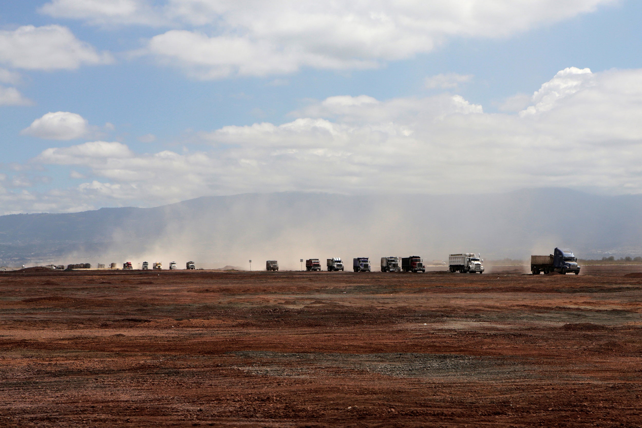 Trucks carrying rocks and soil arrive at the construction site