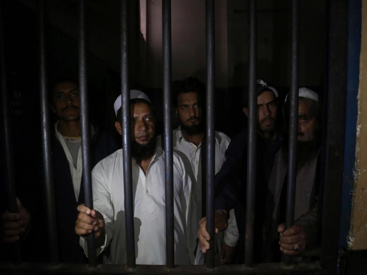 Relatives of a newlywed couple stand behind bars at a police station in Karachi, Pakistan