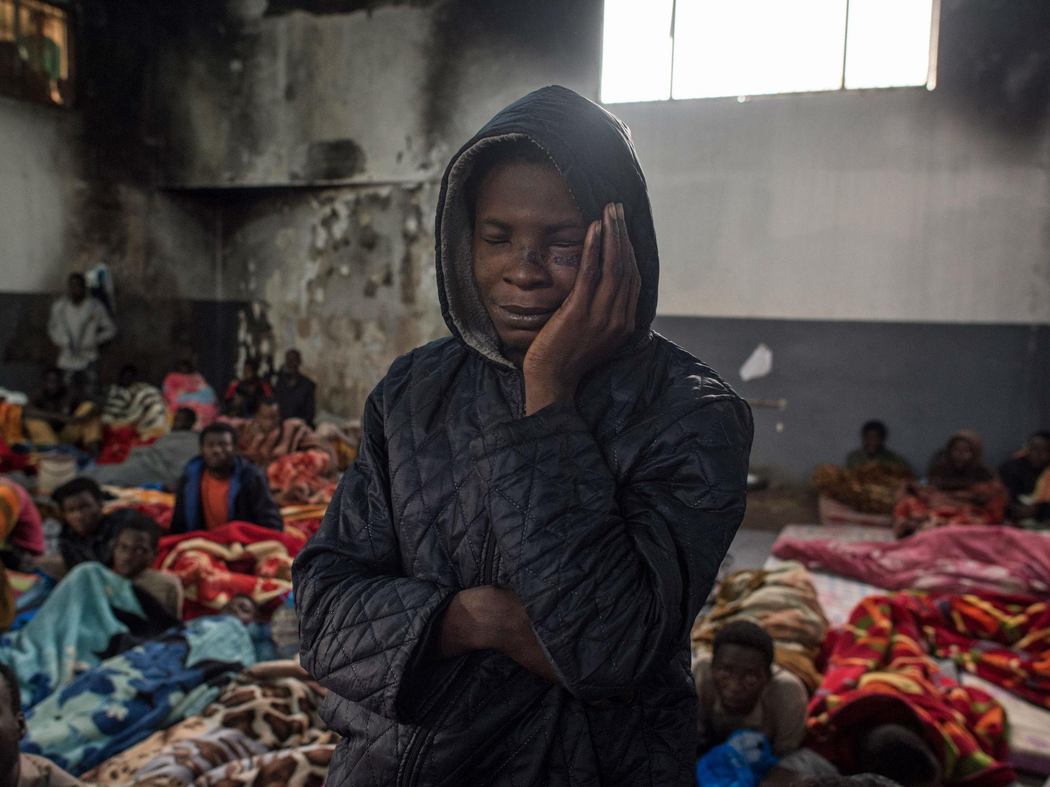 A migrant holds his head as he stands in a packed room at the Tariq Al-Matar detention centre on the outskirts of the Libyan capital Tripoli on November 27, 2017.