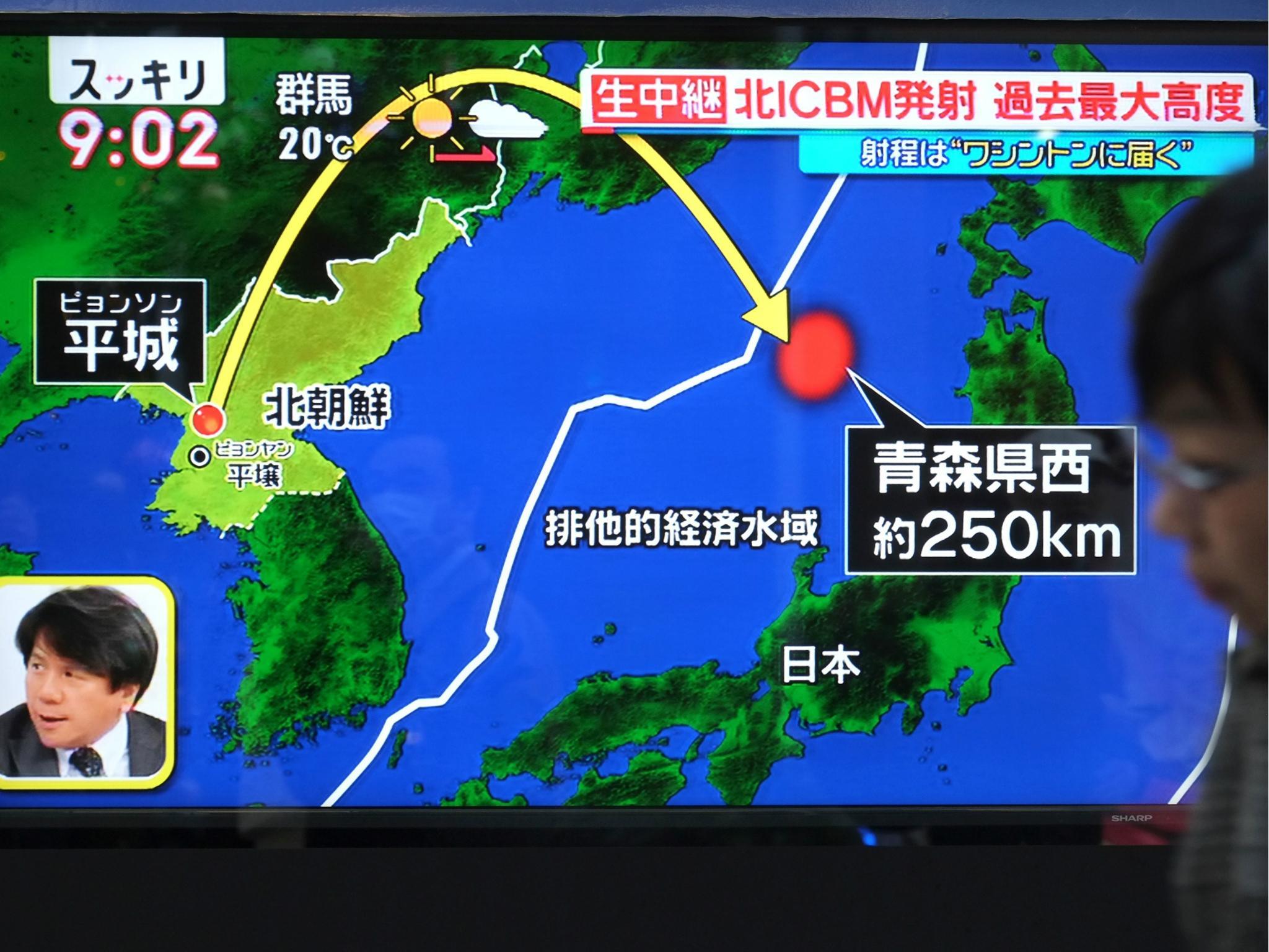 A pedestrian walks in front of a television screen displaying a map of Japan and the Korean Peninsula in Tokyo on 29 November 2017, following a North Korean missile launch.