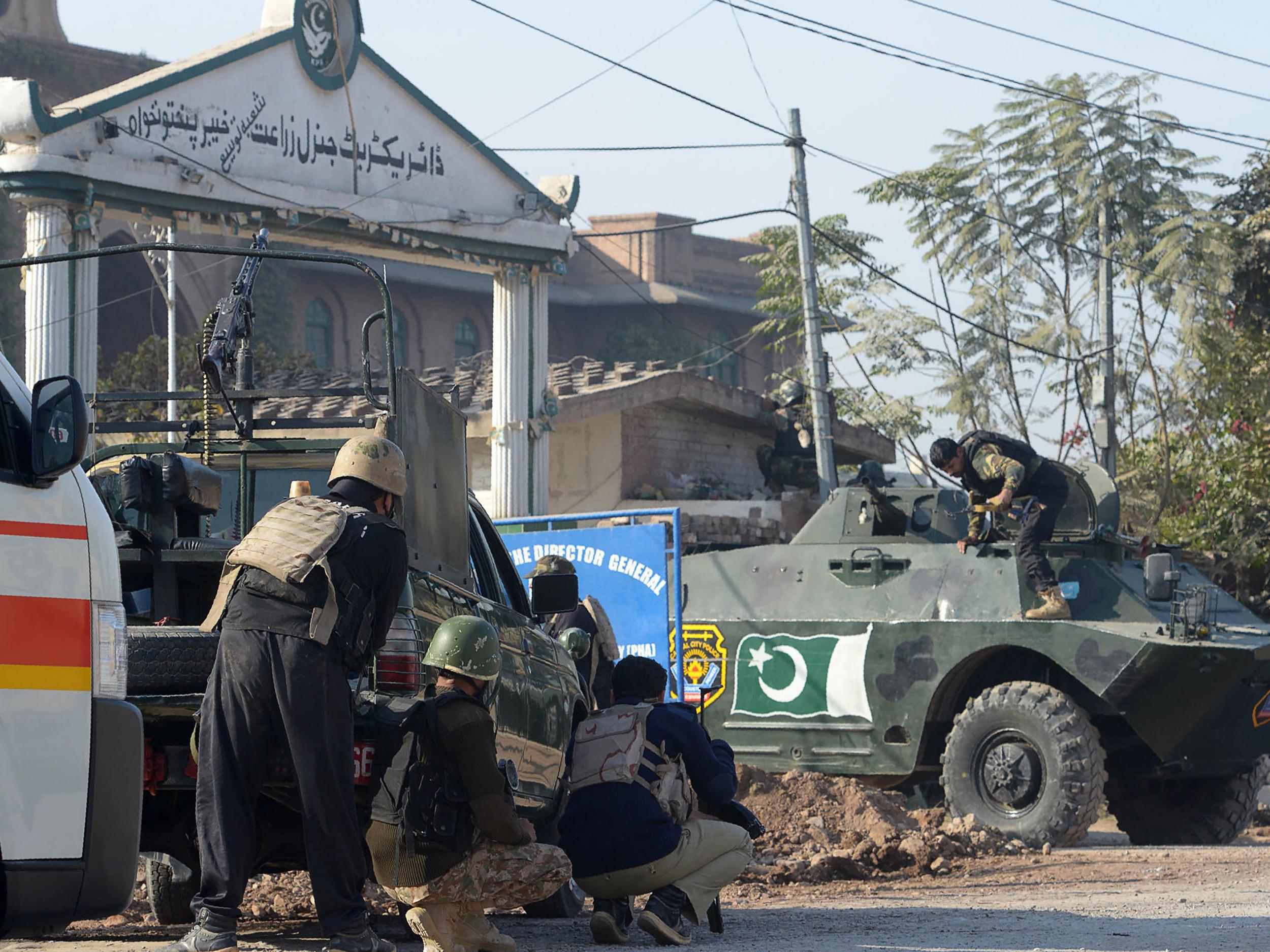 Pakistani security personnel take position outside an Agriculture Training Institute after an attack by Taliban militants in Peshawar