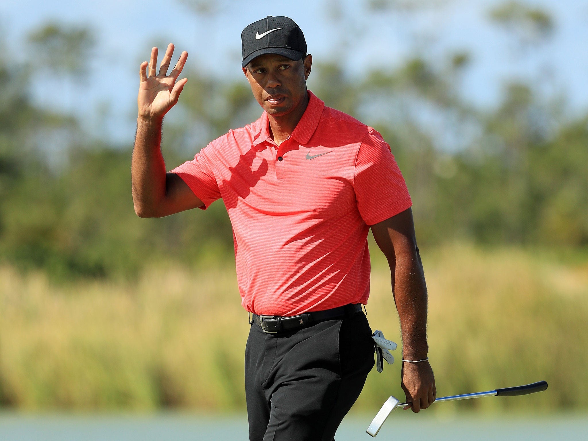 Woods acknowledges the crowds after making his putt on the fourth green