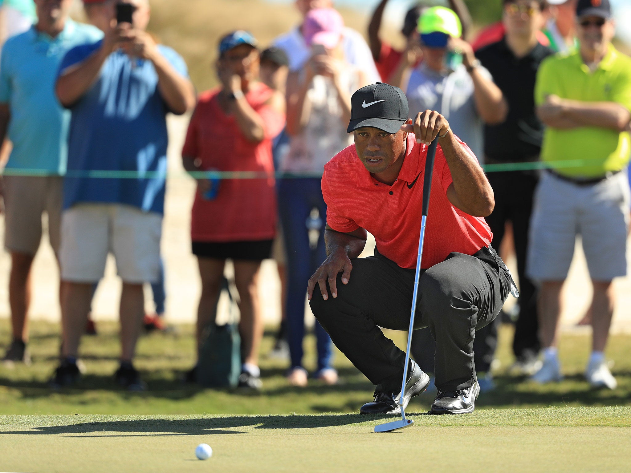 Tiger Woods lines up a putt on the first green