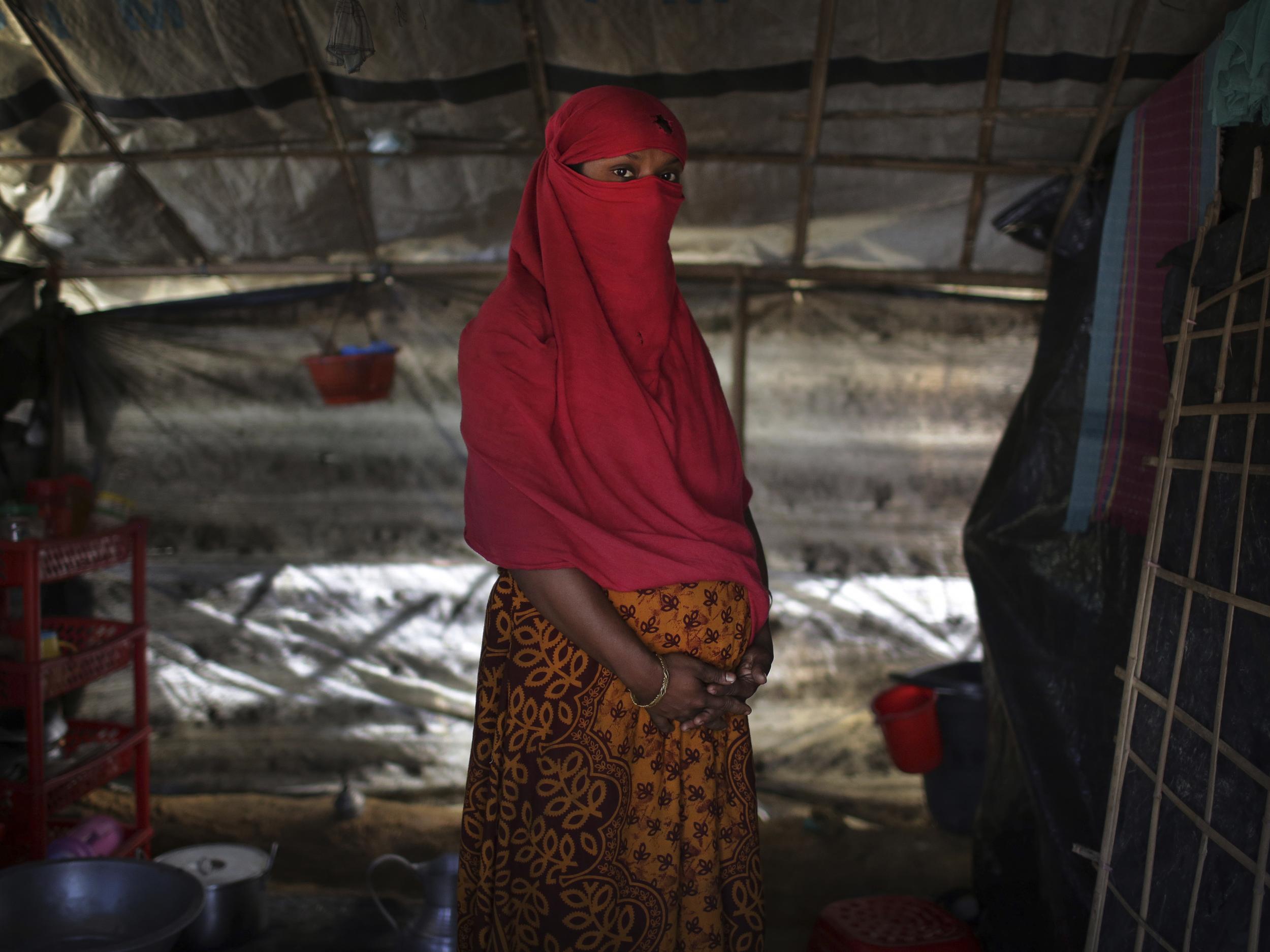 F, 22, who says she was raped by members of Burma's armed forces in June and again in September, clutches her hands around her pregnant belly as she is photographed in her tent in Kutupalong refugee camp in Bangladesh