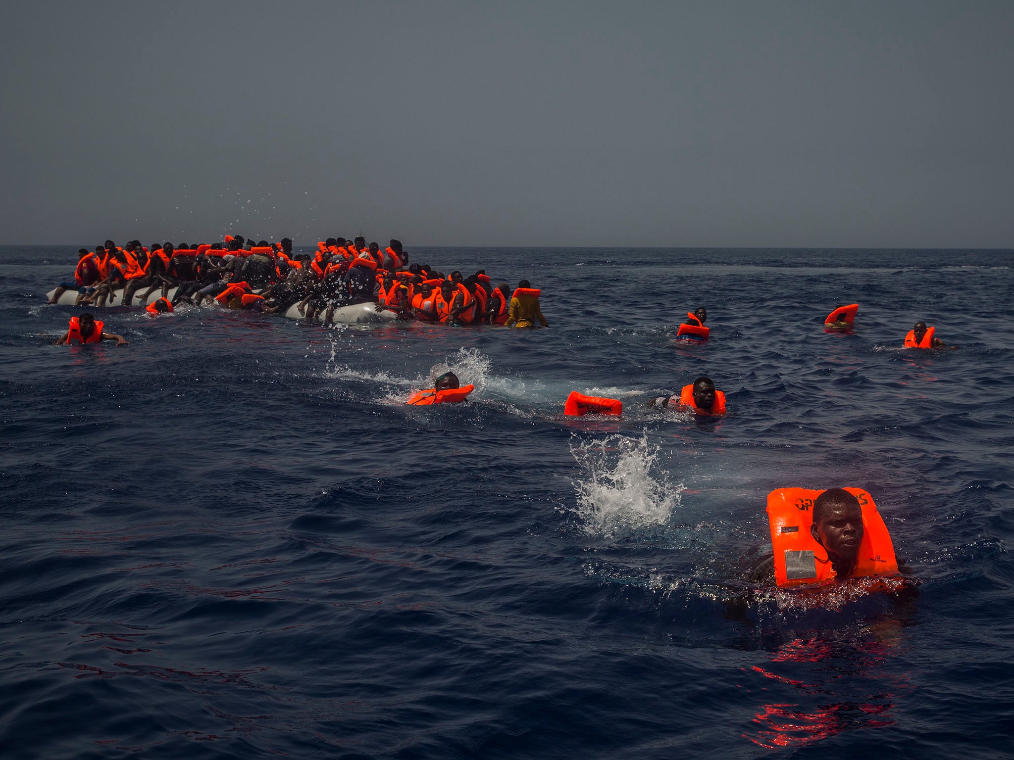 African migrants try to reach a rescue boat from the Spanish aid organisation Proactive Open Arms after falling from a punctured rubber boat in the Mediterranean about 12 miles north of Sabratha, Libya