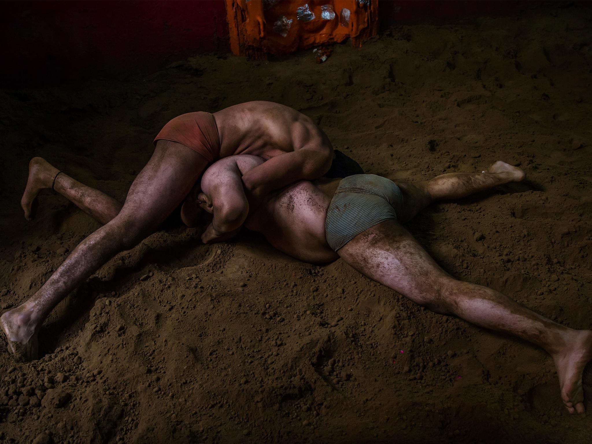 Indian kushti wrestlers fight in a ring in New Delhi, India