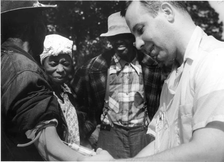 Tuskegee syphilis study doctor injects a subject