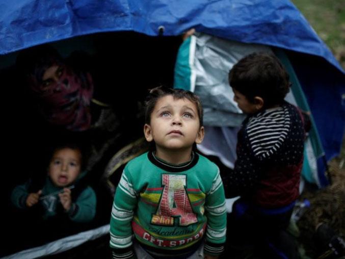 A Syrian refugee boy outside his family tent in a makeshift camp (Reuters)