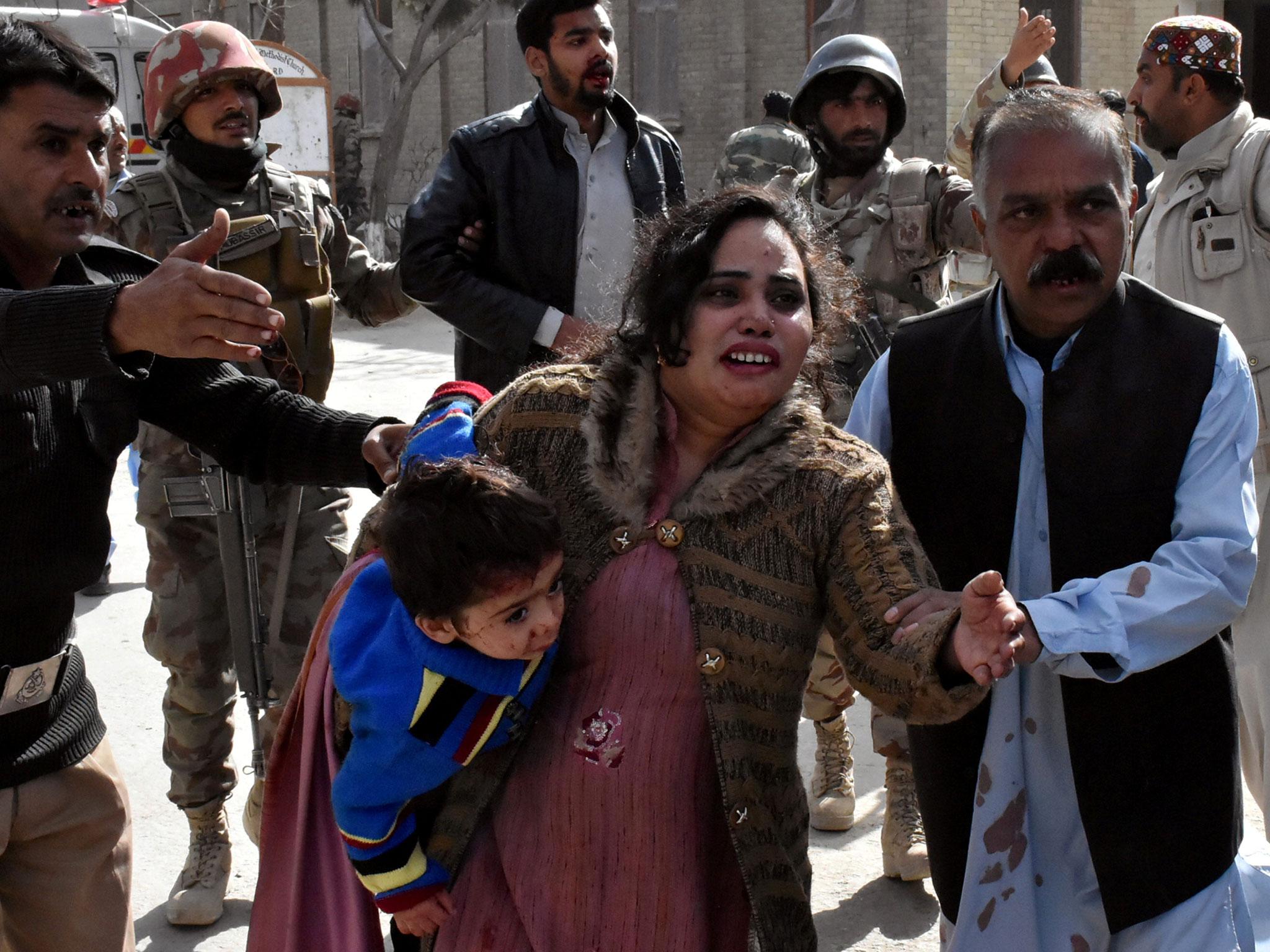 A policeman guides a family away after after gunmen attacked the church (Reuter/Naseer Ahmed)