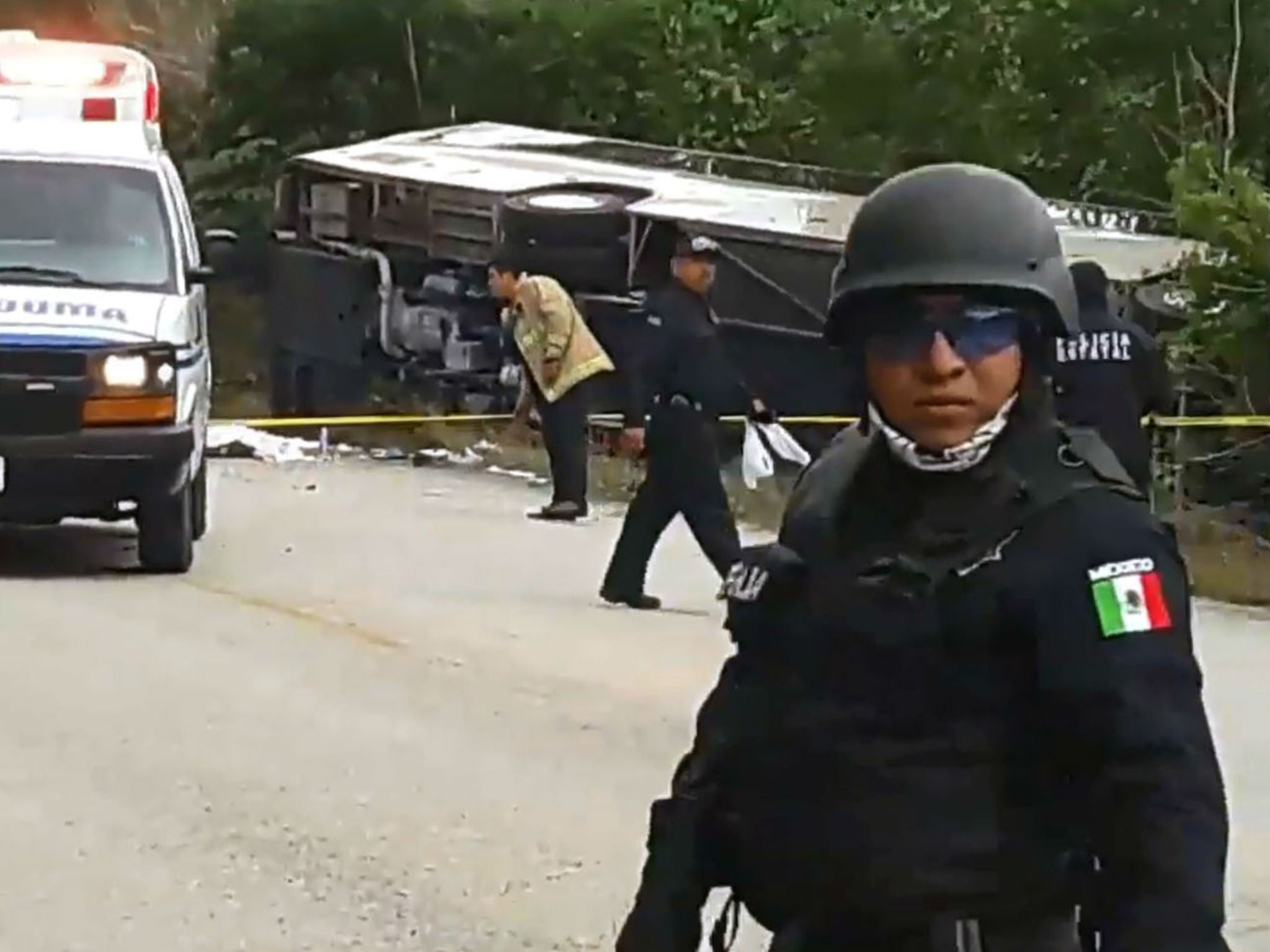 Mexican police officers standing guard in the area where a bus driving tourists to Chacchoben archaeological site overturned