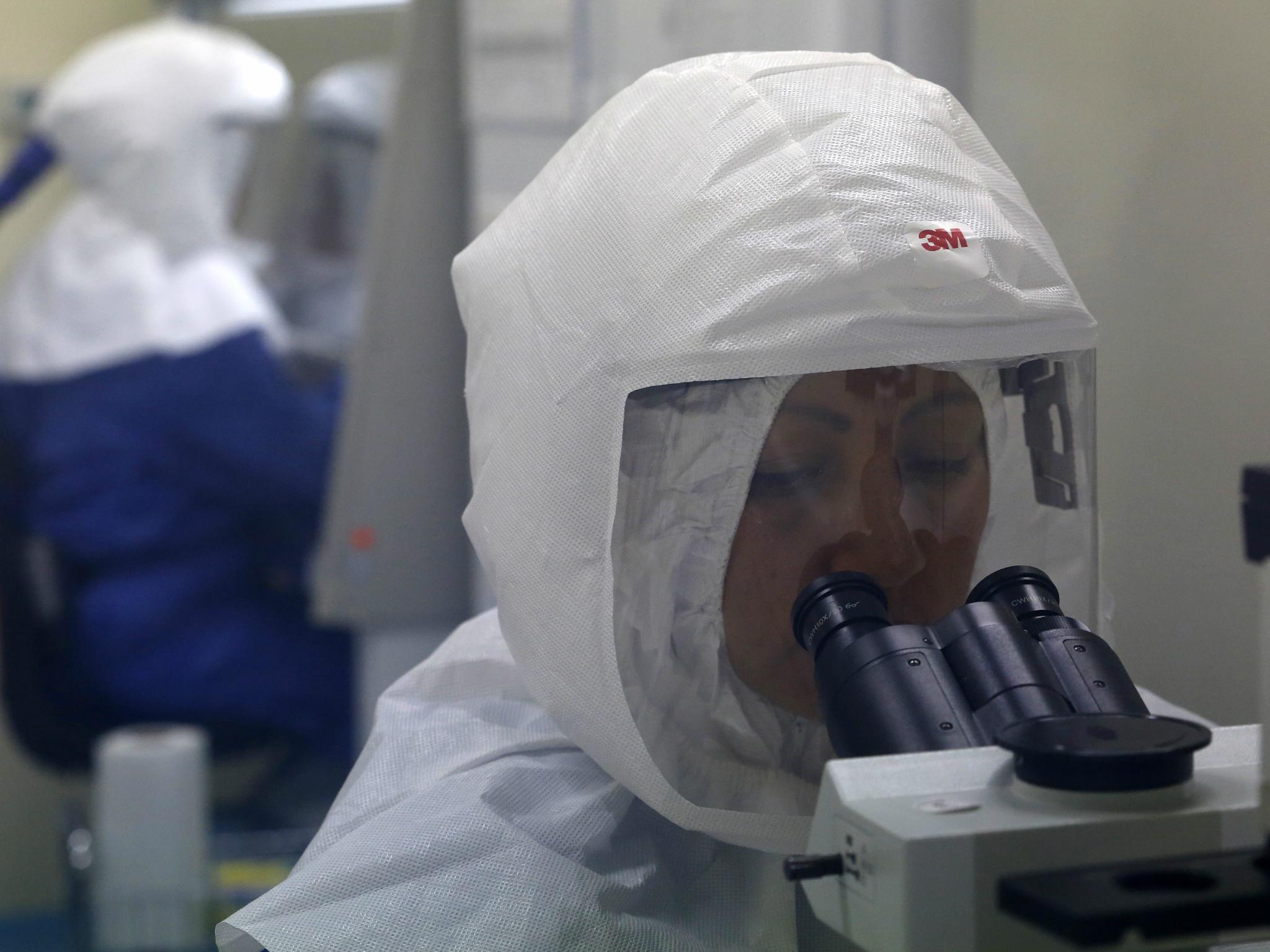 A doctor uses a microscope to look at virus samples in a Biosafety Level III laboratory at the National Institute of Health