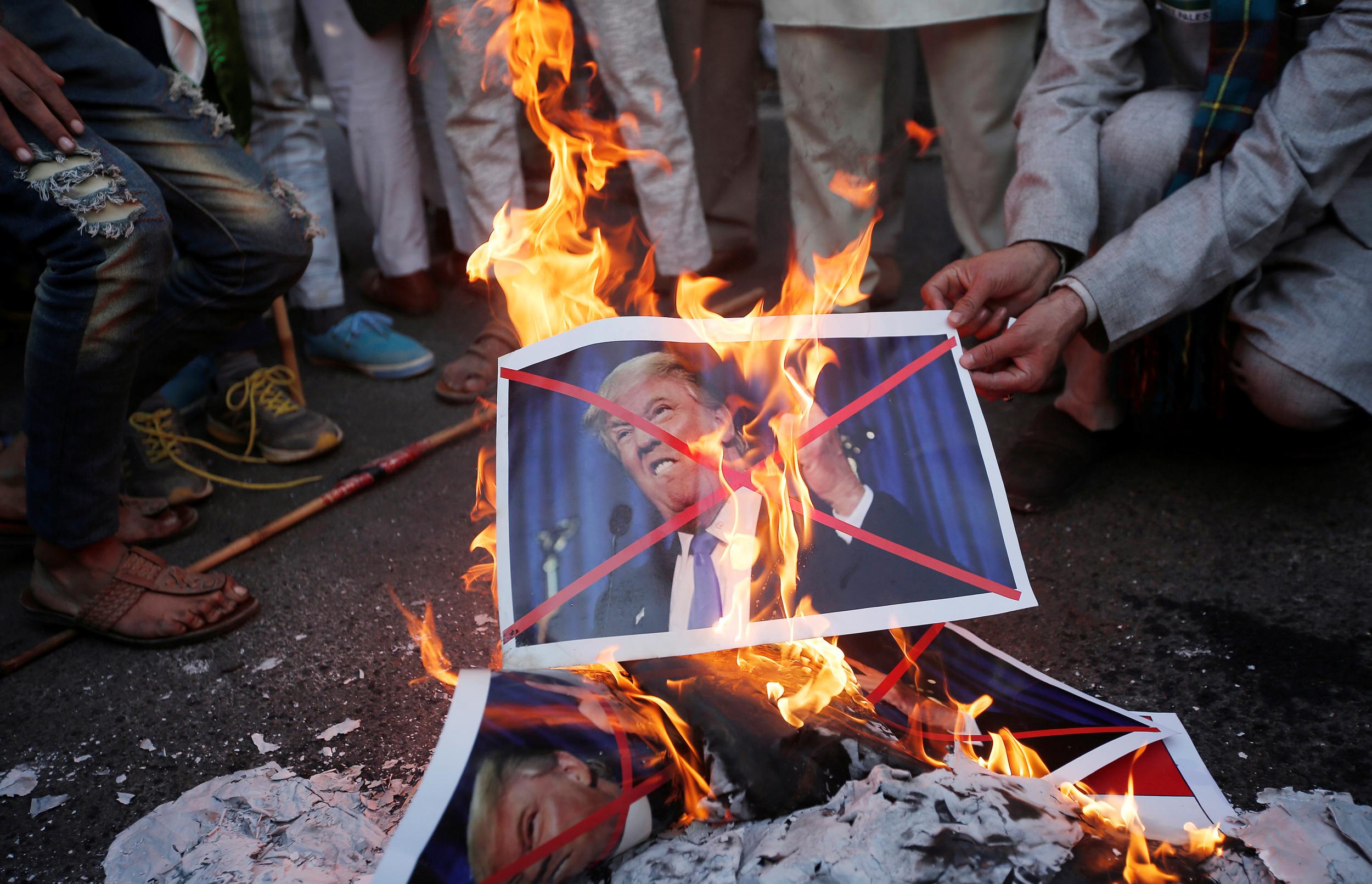 Protesters burn posters of US President Donald Trump during a protest against the US decision to recognise Jerusalem as the capital of Israel