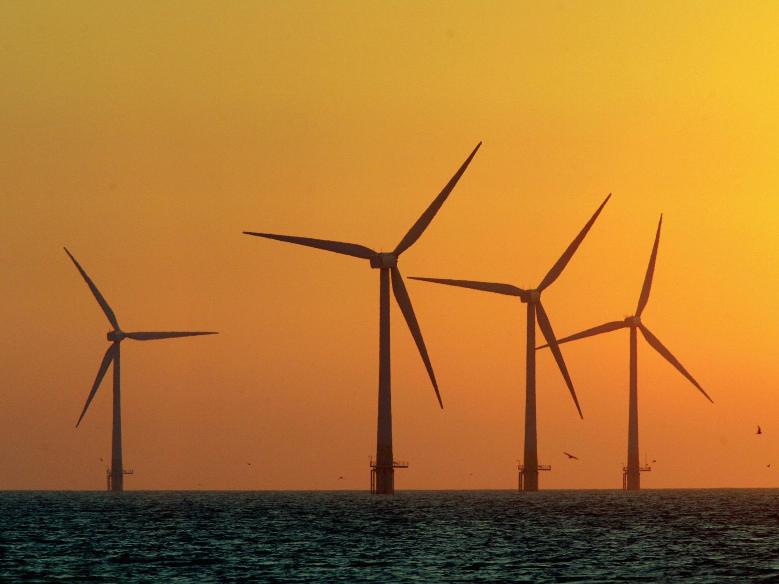 The sun starts to rise behind Britain's largest offshore wind farm off the Great Yarmouth coastline on July 19, 2006 in Norfolk, England.