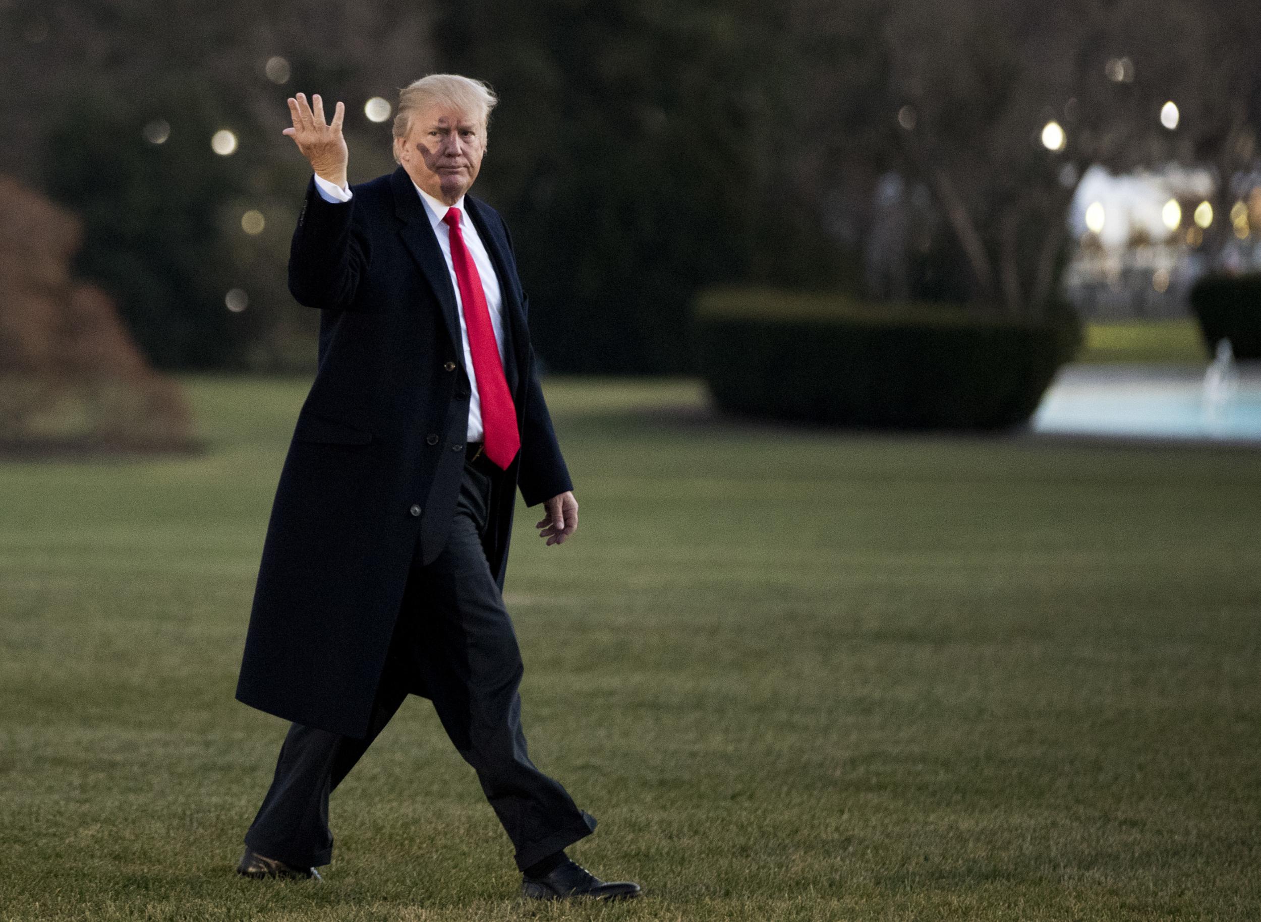 President Donald Trump gestures to reporters asking questions as he returns to the White House on 21 December