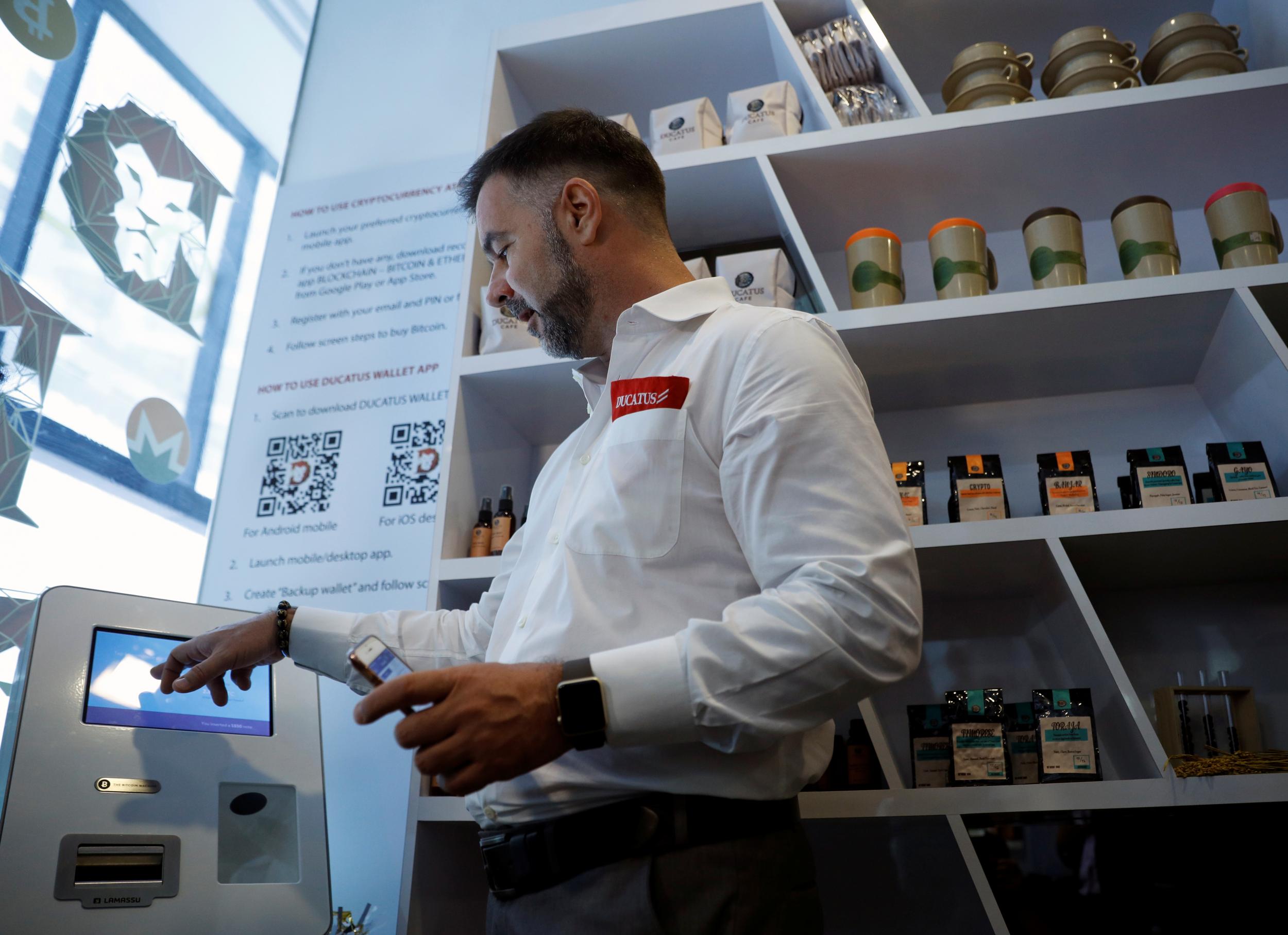 Ducatus CEO Ronny Tome makes a deposit at a bitcoin ATM during the opening of their cashless cafe