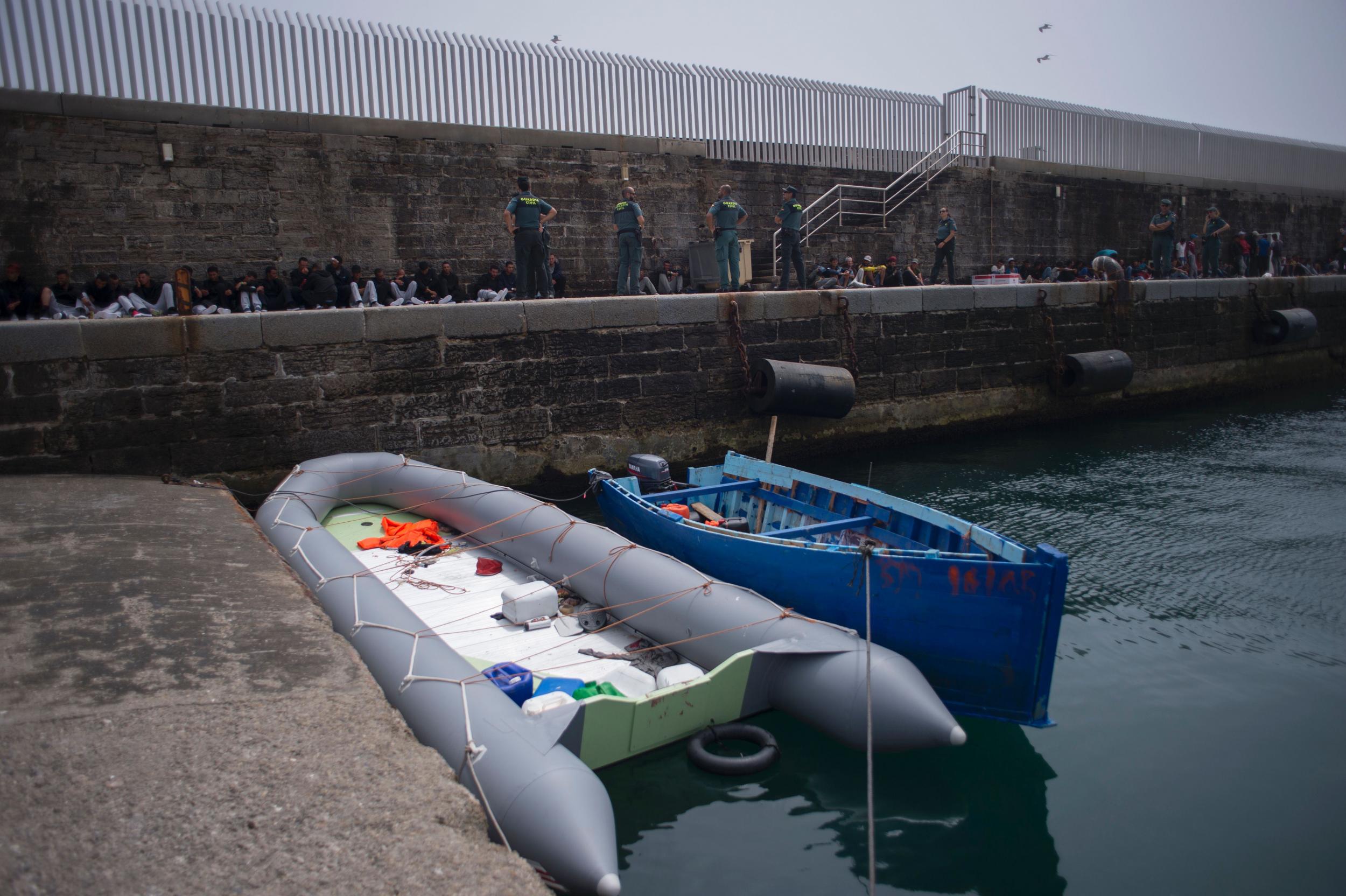 Two makeshift refugee boats moor in the foreground as would-be immigrants rest after being rescued in the waters of the Strait of Gibraltar, in the port of Tarifa (AFP/Getty)