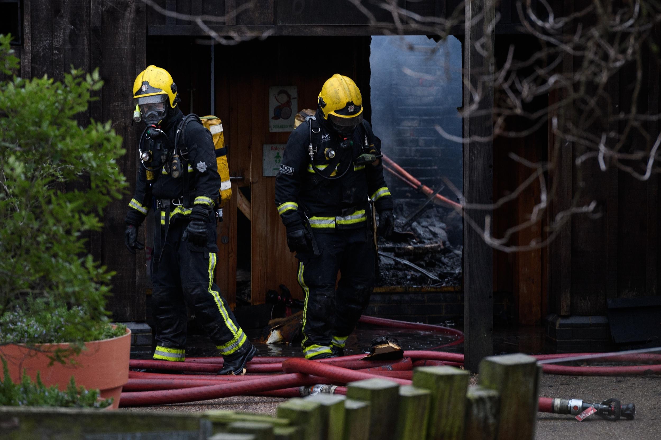 Firefighters move equipment and survey the damage after a fire destroyed buildings at London Zoo (Getty)