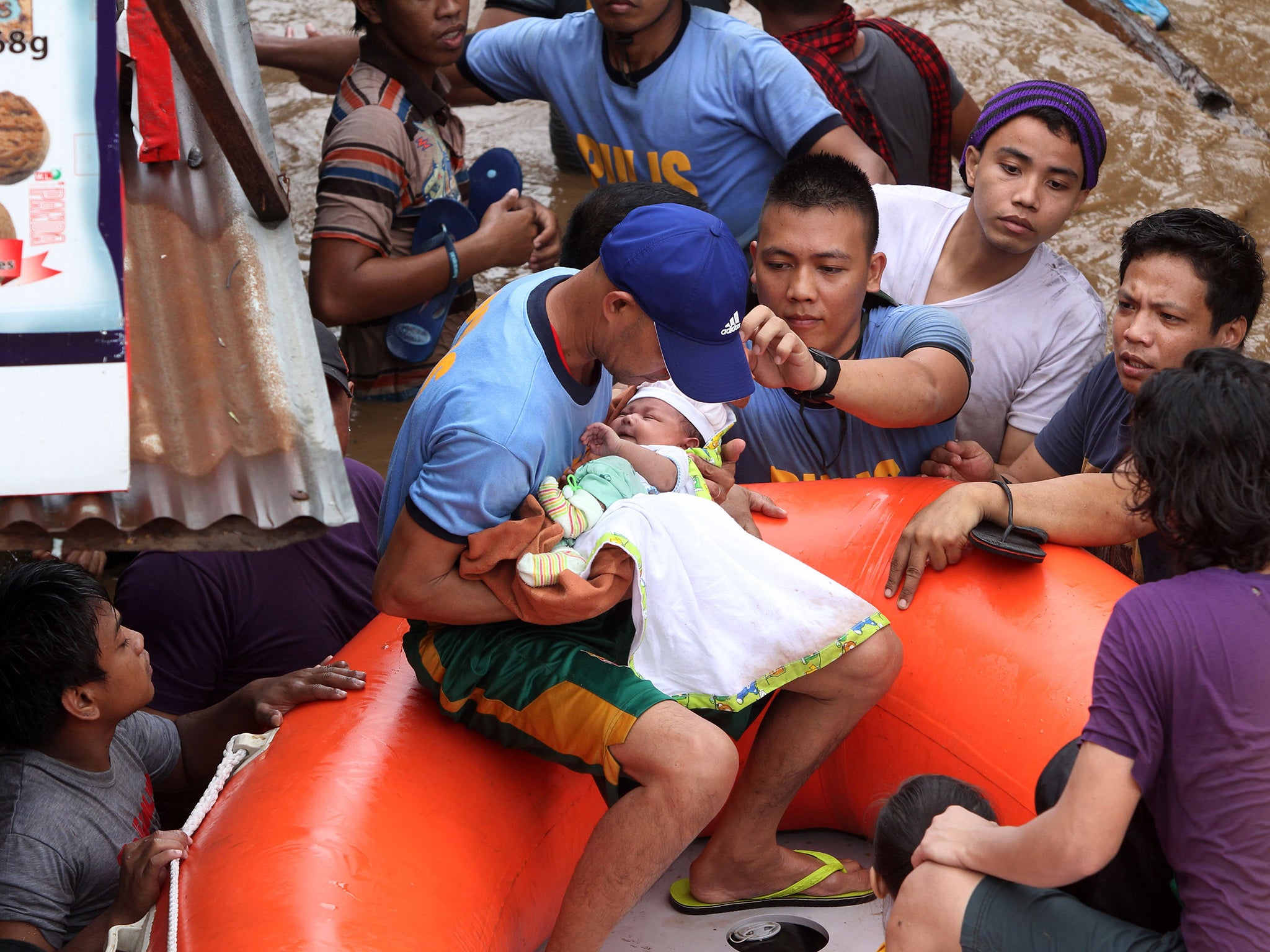 Policemen evacuate a baby after the Cagayan River swelled, caused by heavy rains brought by Tropical Storm Tembin