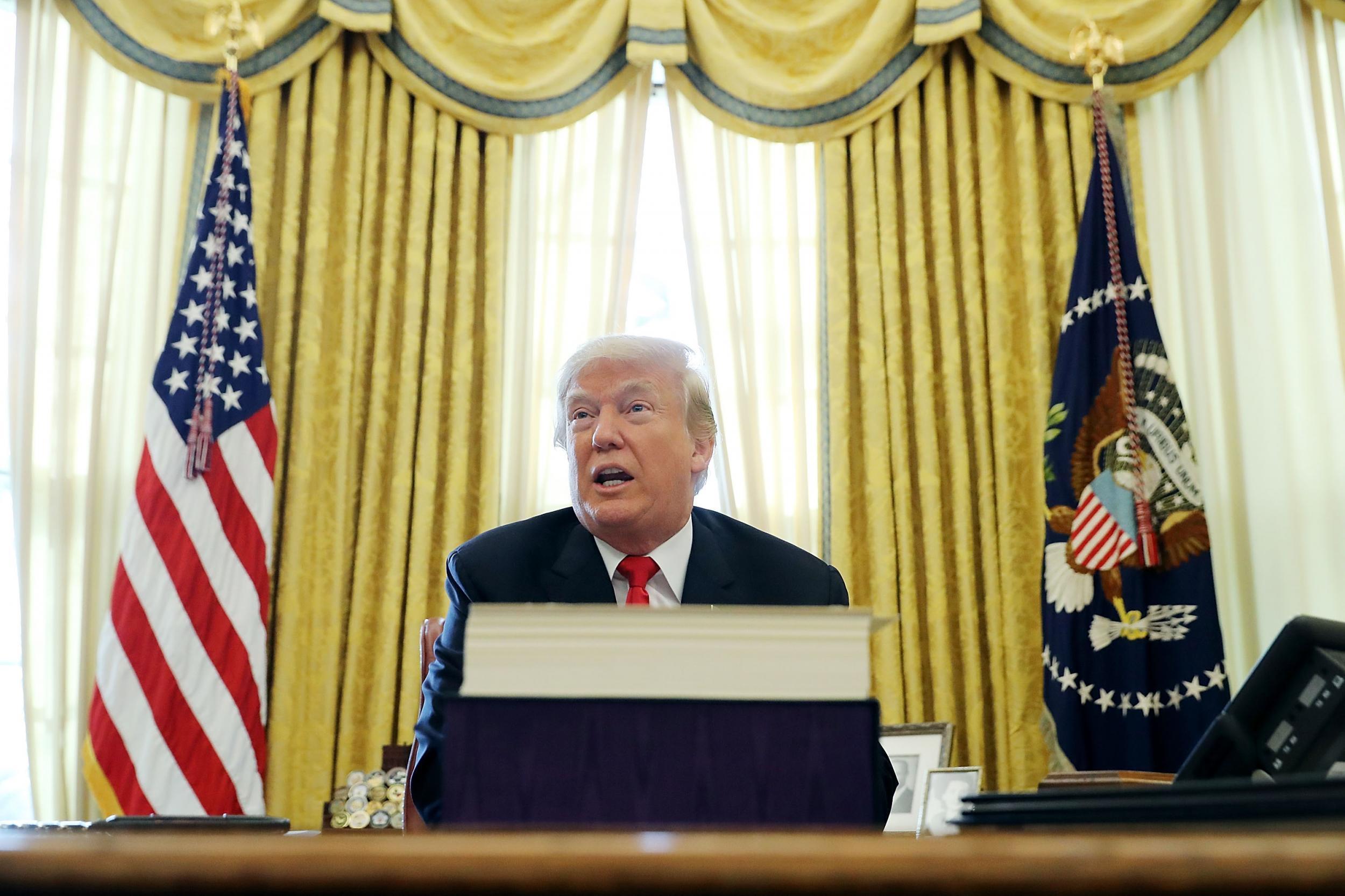 President Donald Trump talks with journalists after signing tax reform legislation into law in the Oval Office