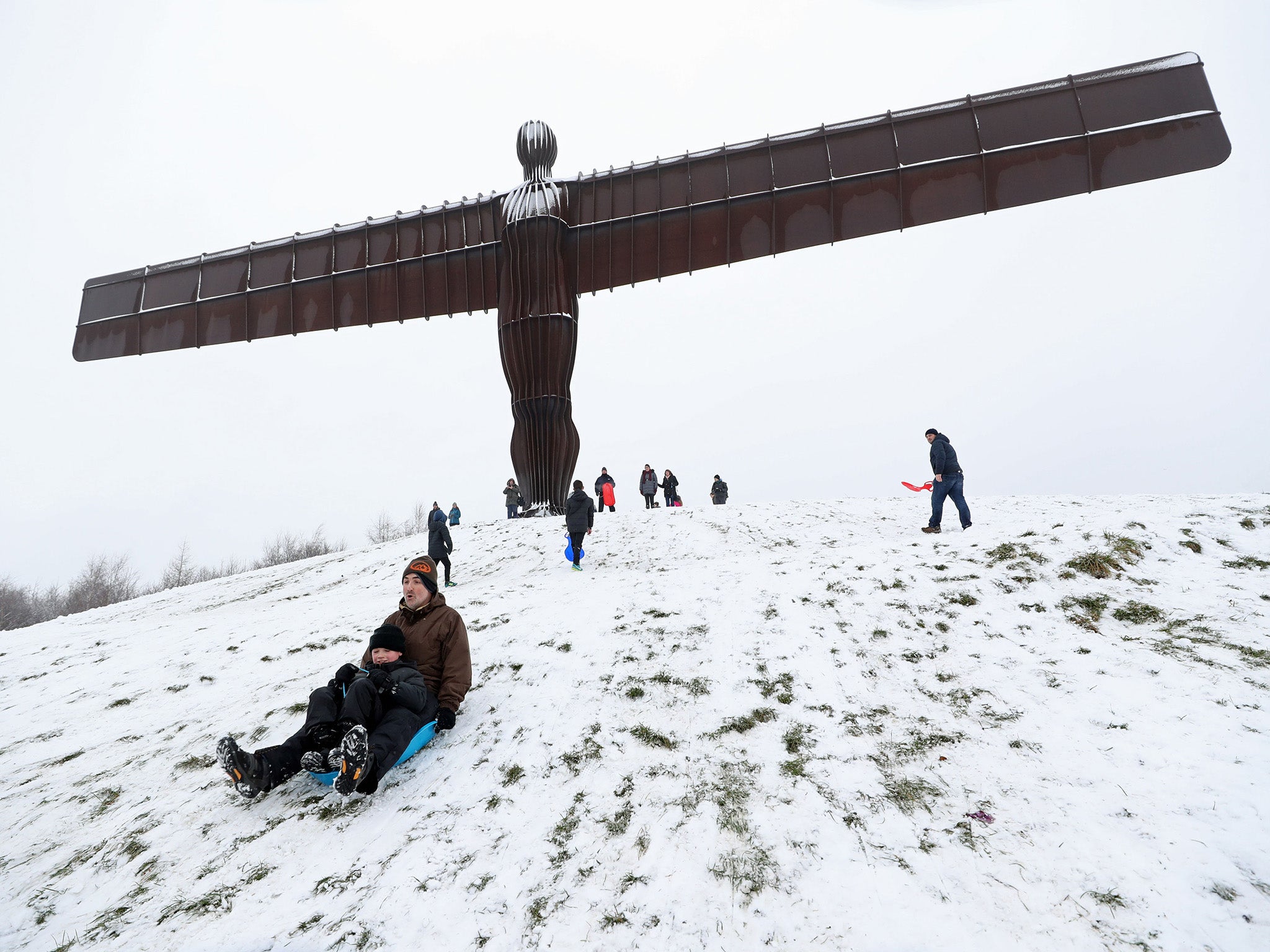 Families sledging under the Angel of the North