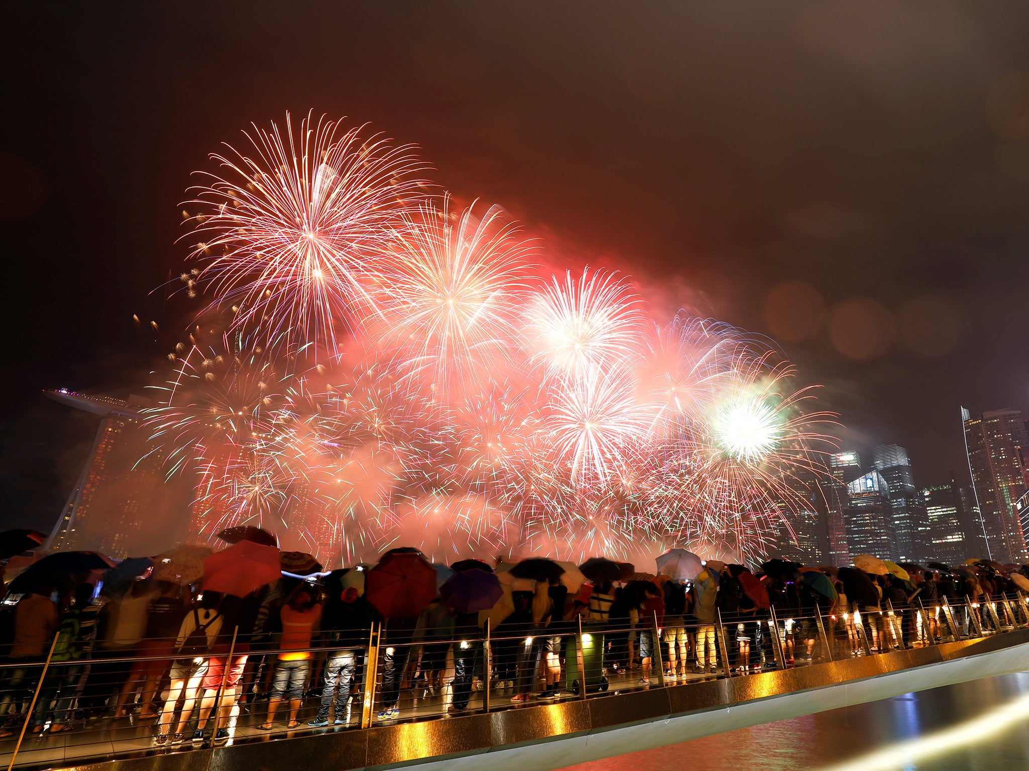 People watch fireworks in the rain at the Marina Bay ahead of the New Year in Singapore