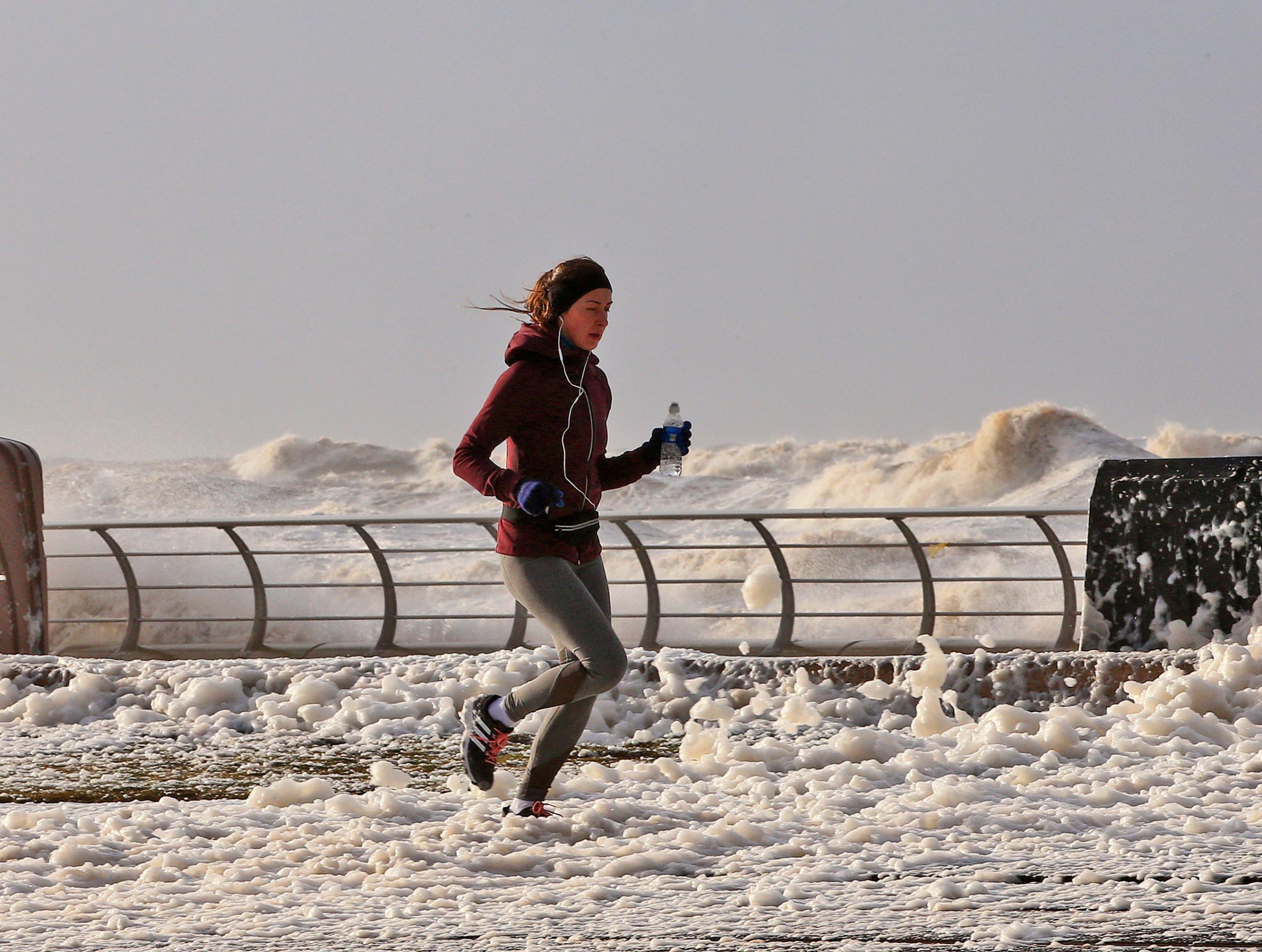 A woman jogs through sea foam in Blackpool as Storm Eleanor lashed the UK