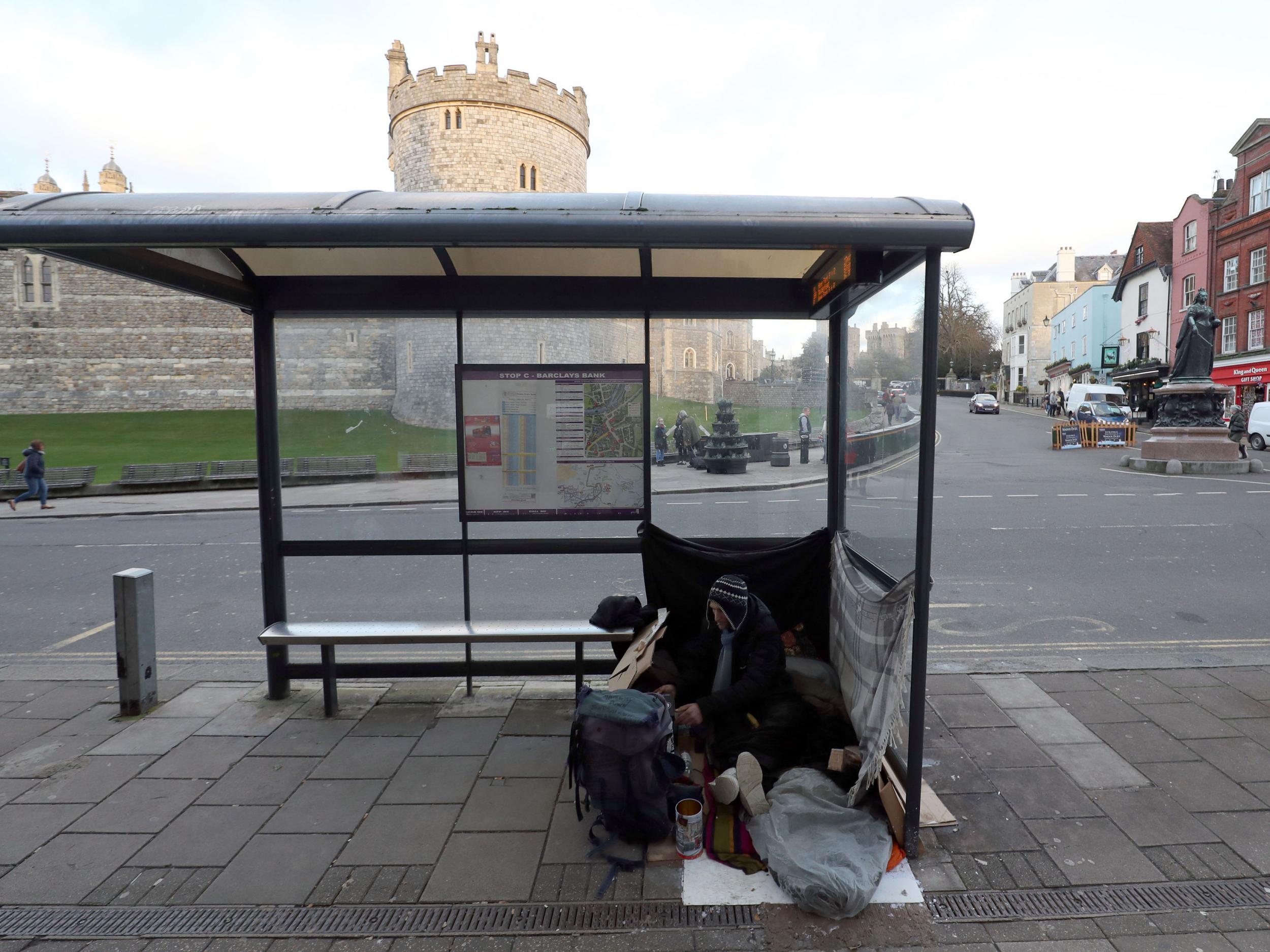 A homeless man with his possessions at a bus stop near Windsor Castle, Berkshire