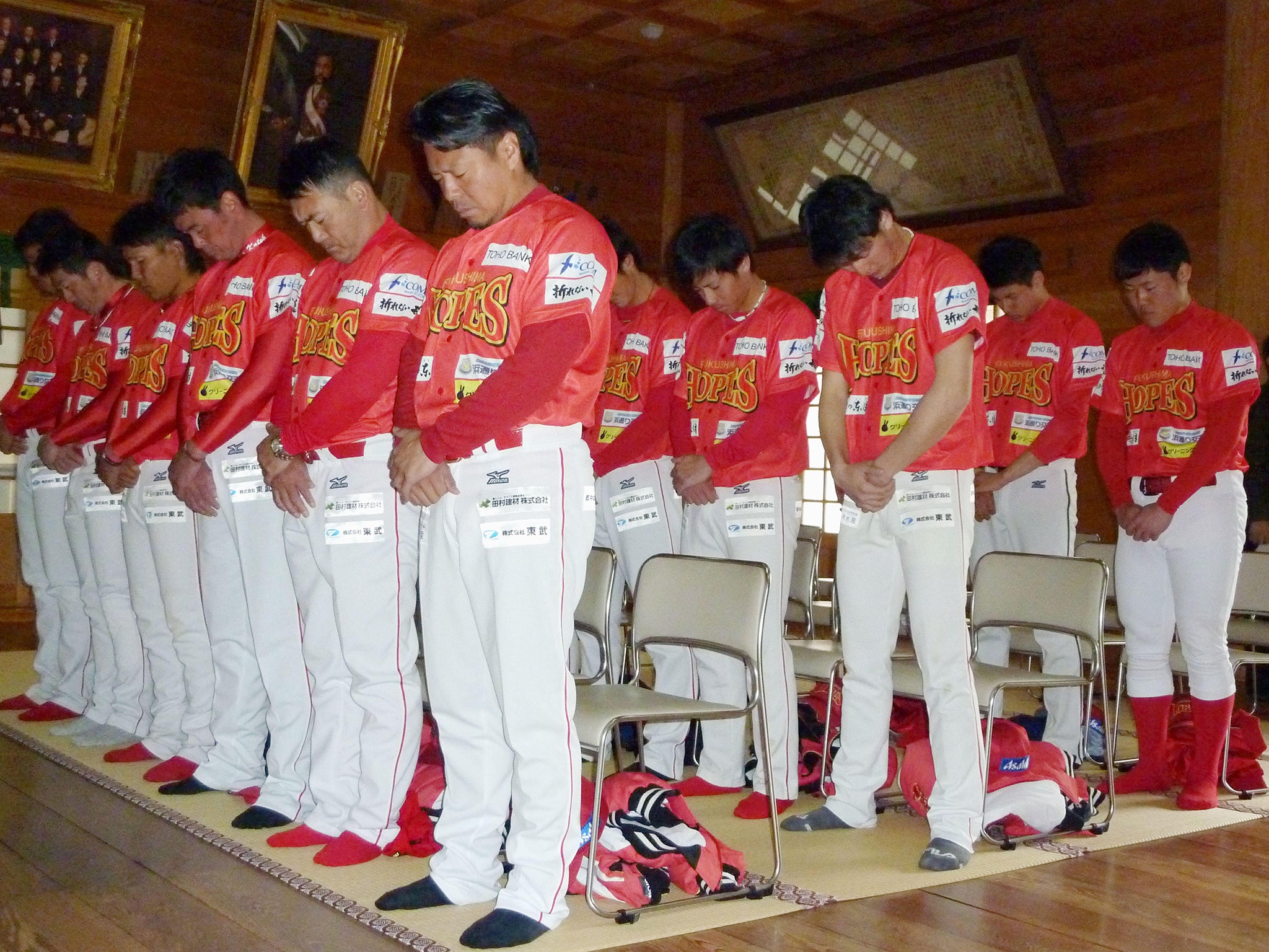 Akinori Iwamura (front) and other members of the Fukushima Hopes with their heads bowed in prayer ahead of the start of the 2016 season