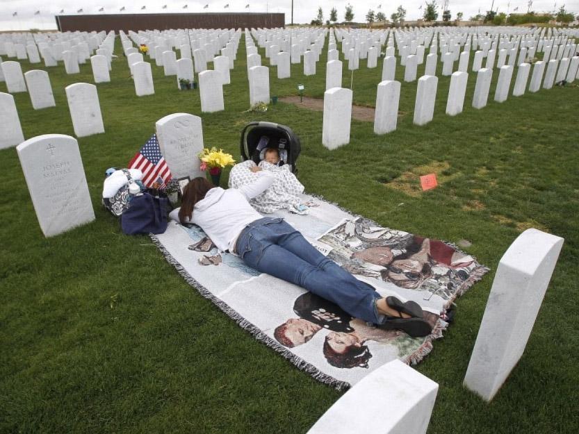 Jenn Budenz lies on a blanket with her two-month-old son, AJ, as they visit the grave of Major Andrew Budenz at Miramar National Cemetery on 22 May 2014 in San Diego