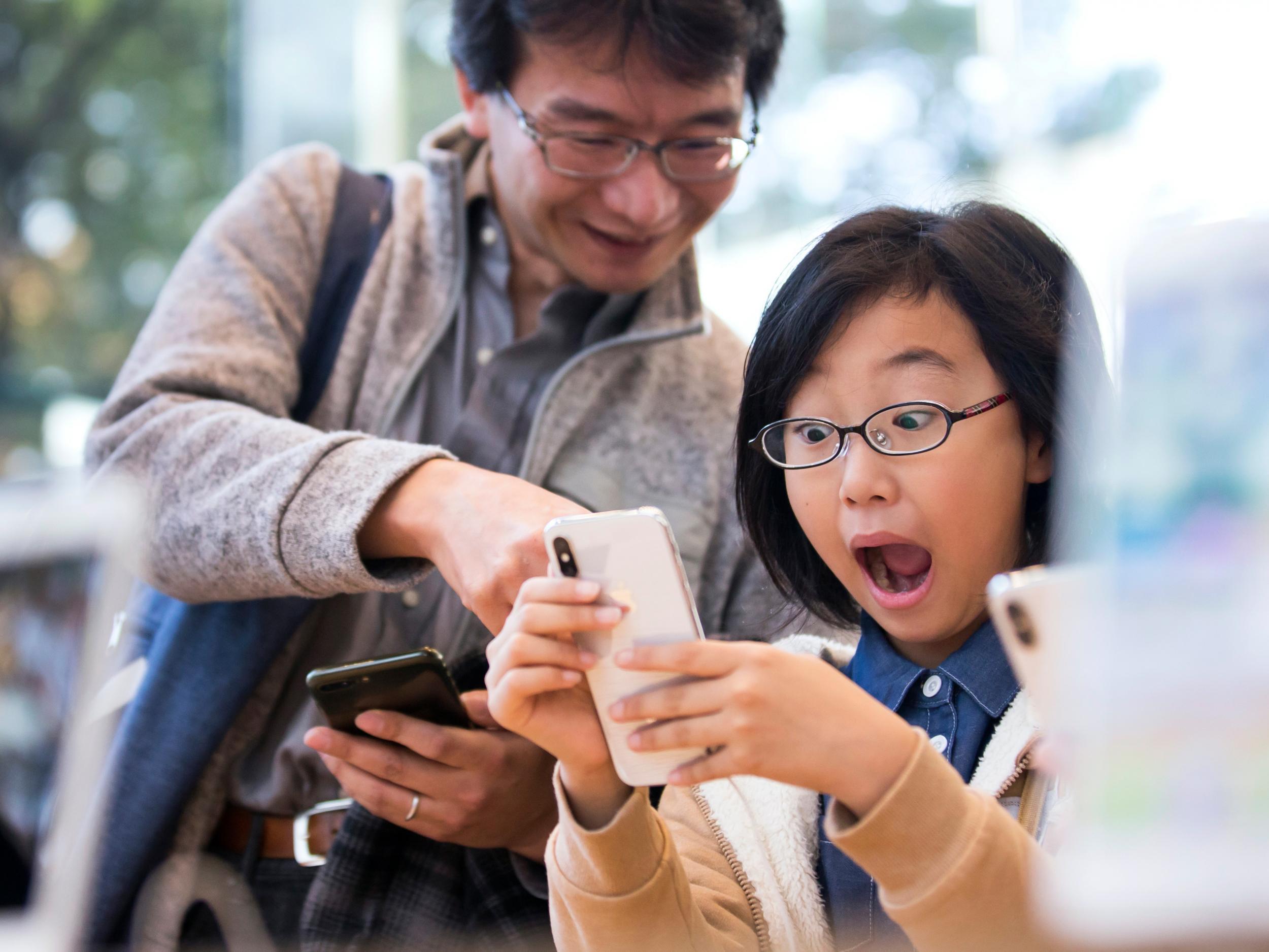 A girl reacts as she tries an iPhone X at the Apple Omotesando store on November 3, 2017 in Tokyo